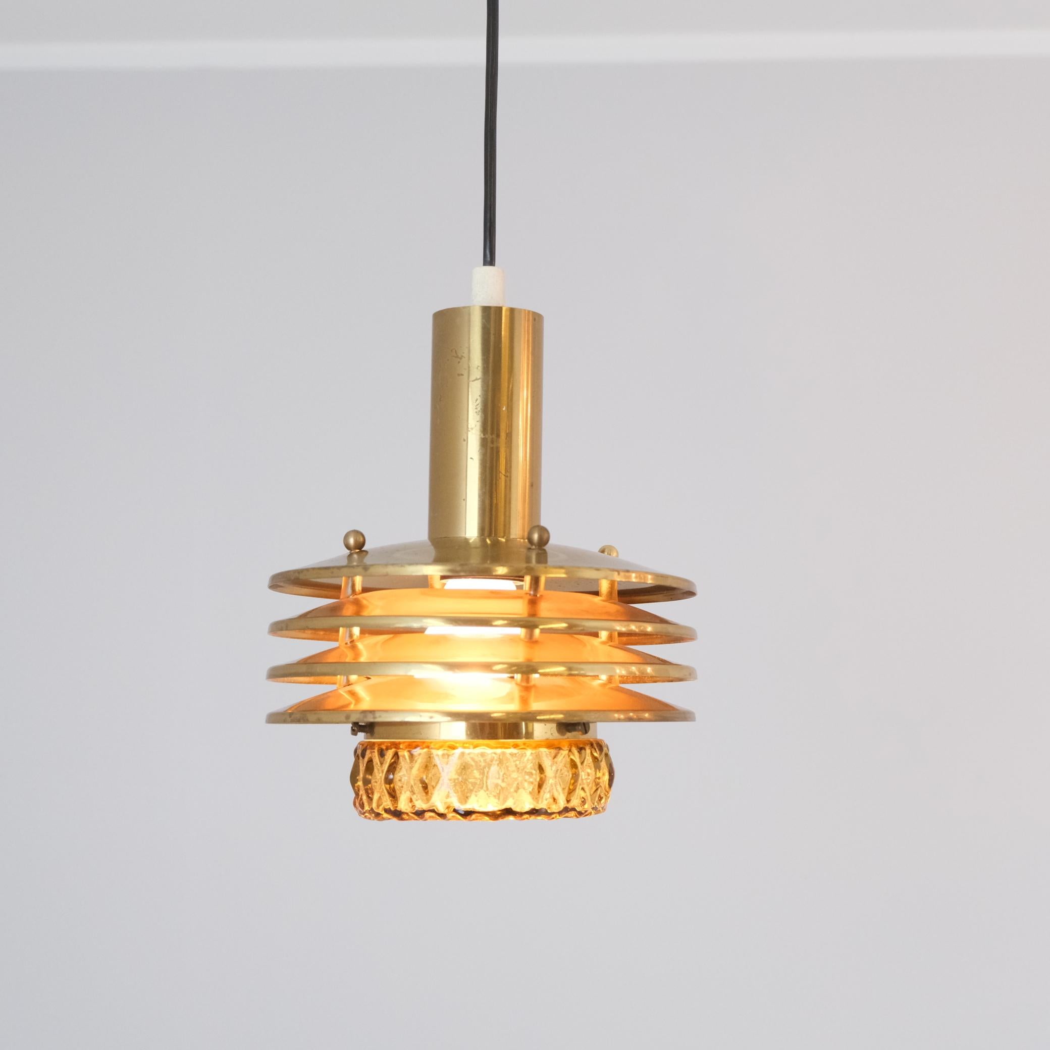 Un affascinante ciondolo di metà secolo del designer finlandese Kai Ruokonen (Kai Finnmark), realizzato in doghe di ottone con un diffusore in vetro color fumé. Compatto in scala ma pieno di carattere, questo pendente bijou cattura l'essenza dello