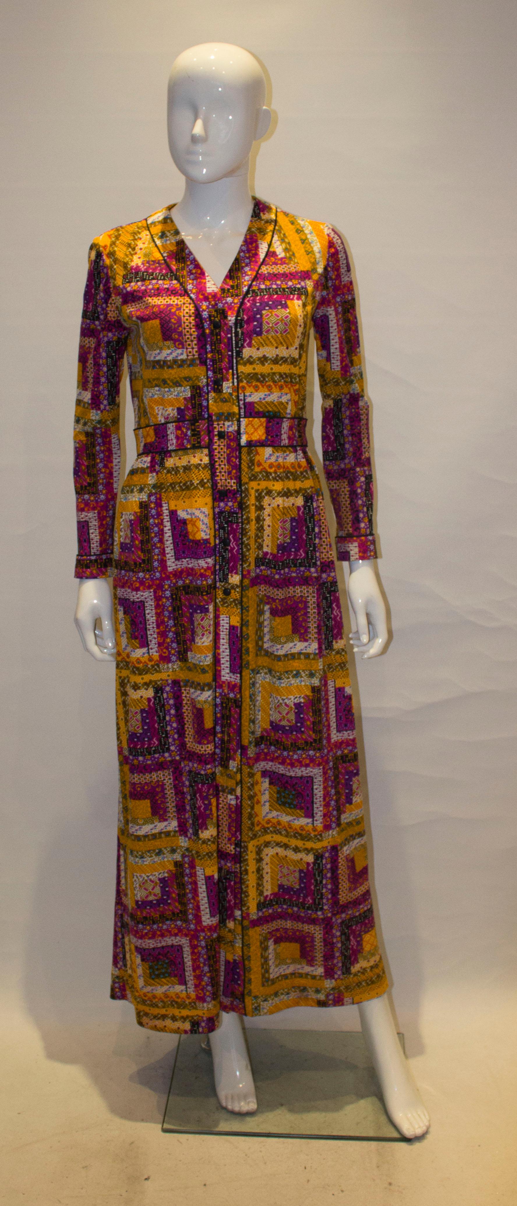 A chic , colourful gown by Fiorenza in shades of orange, purple and white. The dress has a  button through front opening with black trim,  a v neckline and gathering at the waist.