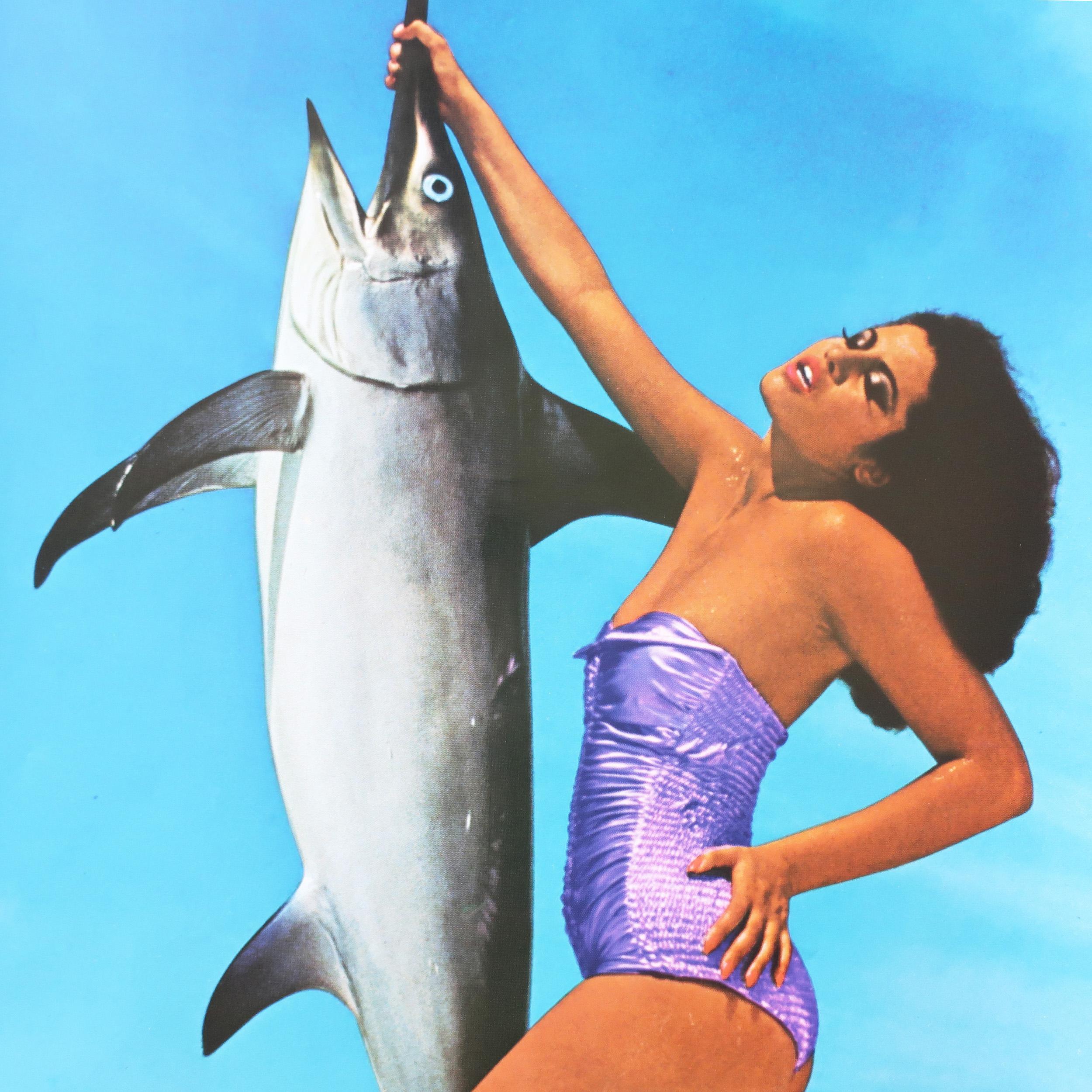 Ein altes und seltenes Fiorucci-Plakat mit einem ikonischen Bild von  schöne Frau im Badeanzug, die einen Schwertfisch am Schnabel hält.  Schwarze Haare, lila Badeanzug und Make-up vor dem Hintergrund eines wolkenverhangenen Himmels.  Der Schriftzug