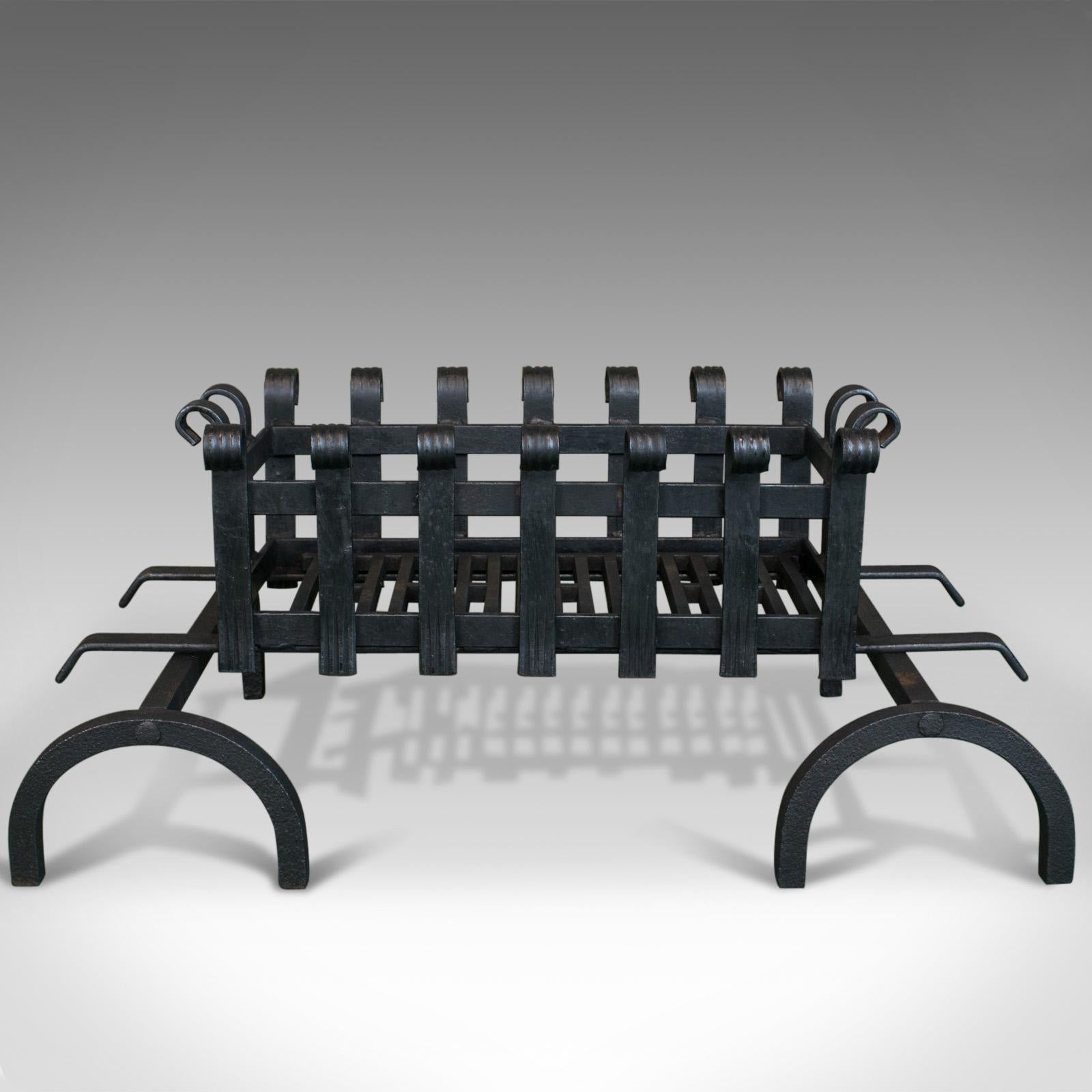 This is a vintage fire basket sitting on a pair of andirons. An English, iron fire grate dating to the mid-20th century.

A quality fire basket resting above a sturdy pair of fire dogs
Hand forged iron grate and basket
Charming hoop andiron legs