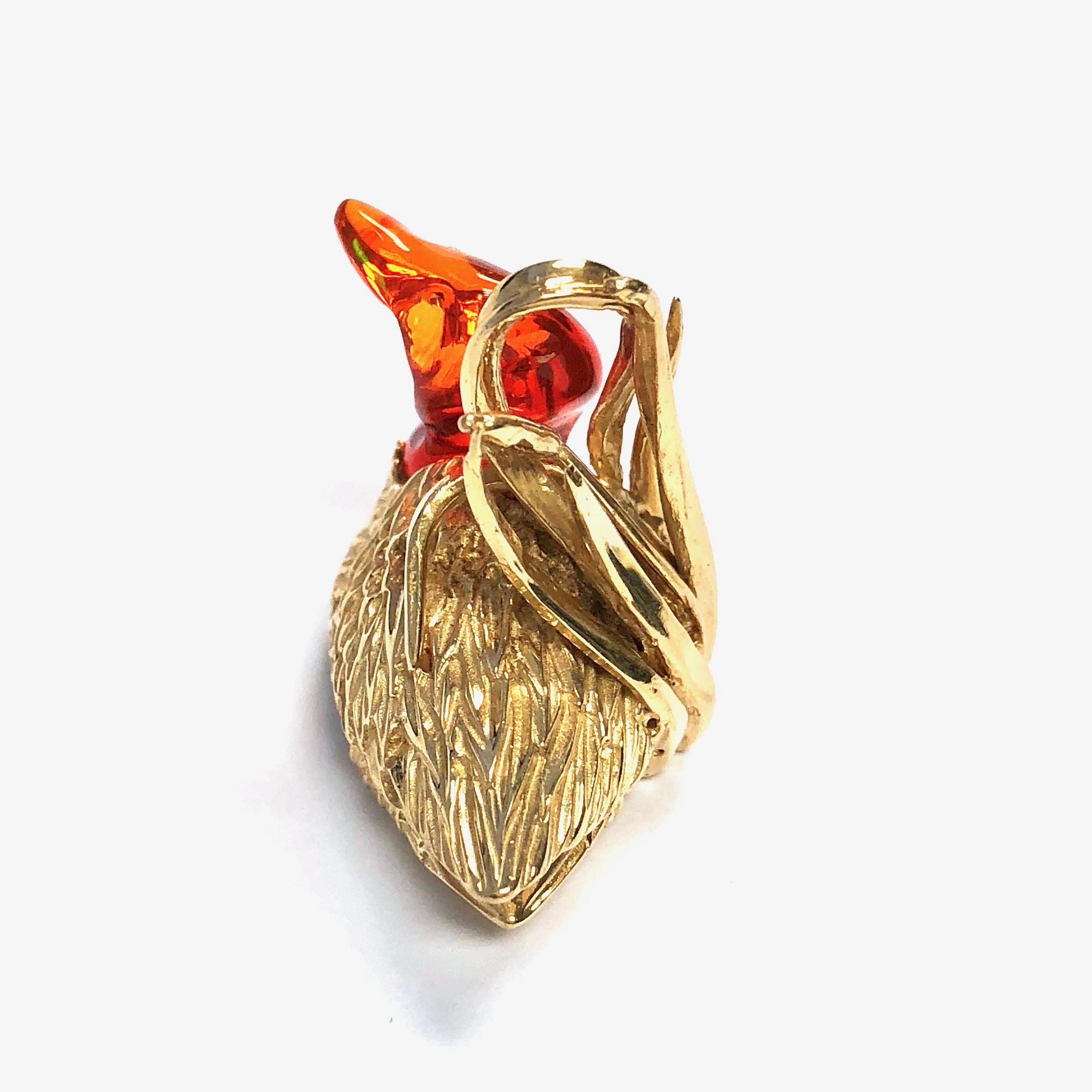This one-of-a-kind bird pendant is crafted in 14K yellow gold, featuring a free-form fire opal as the duck's head and neck, supported by the textured gold body and reed as the loop in the back. The opal displays a strong fire of colors. Truly a
