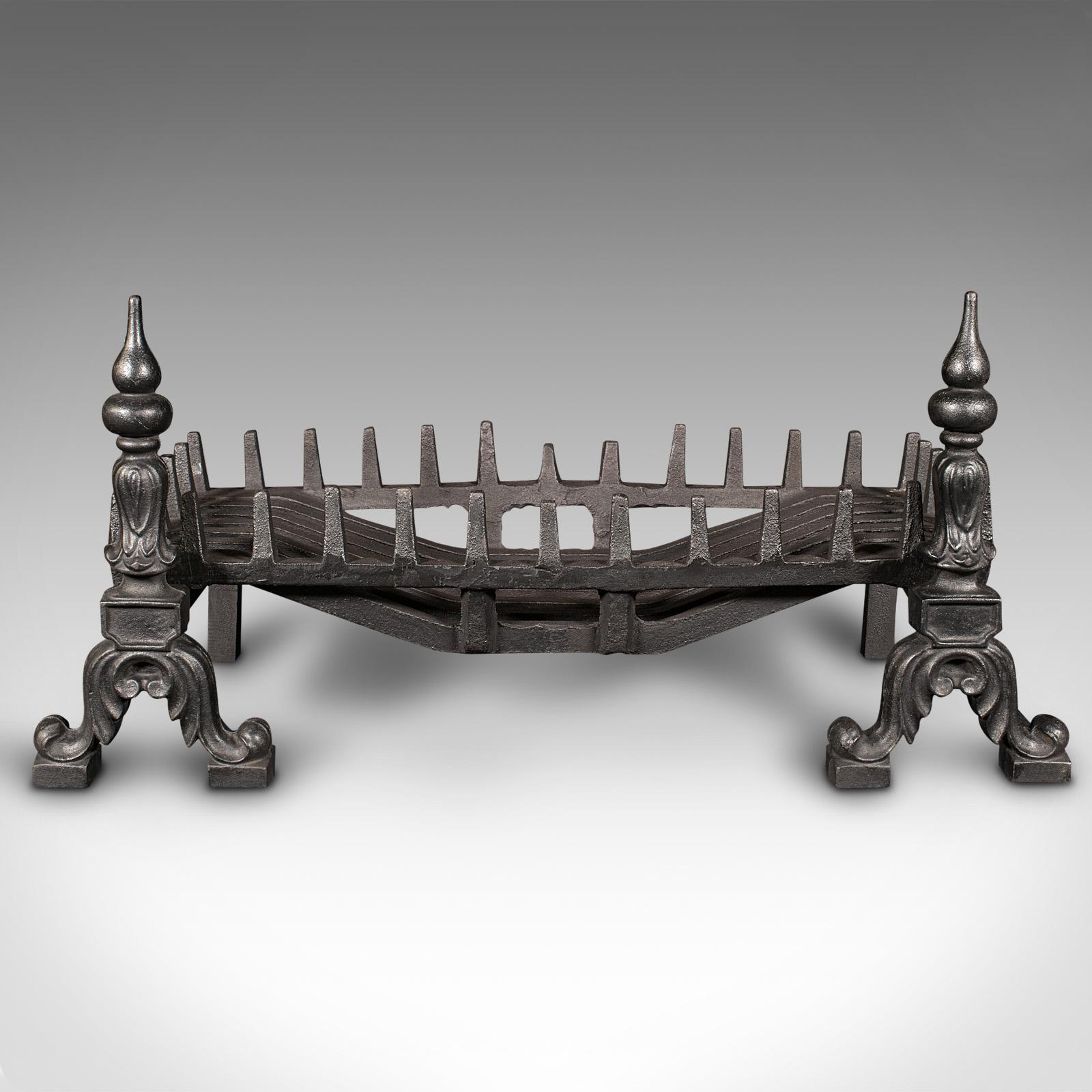 This is a vintage fireplace set. An English, cast iron fire basket with andirons, dating to the mid 20th century, circa 1940.

Of traditional taste, and shallow proportion
Displays a desirable aged patina and in good order
Wide fire basket with