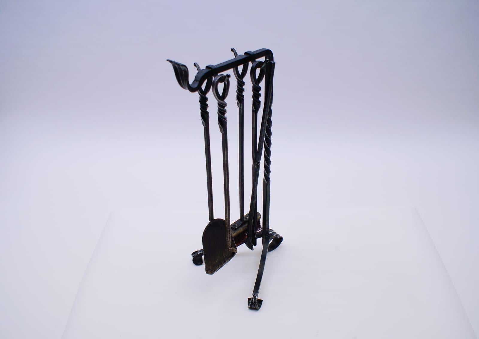 A set of four arts fire utensils on a cast iron stand.

 