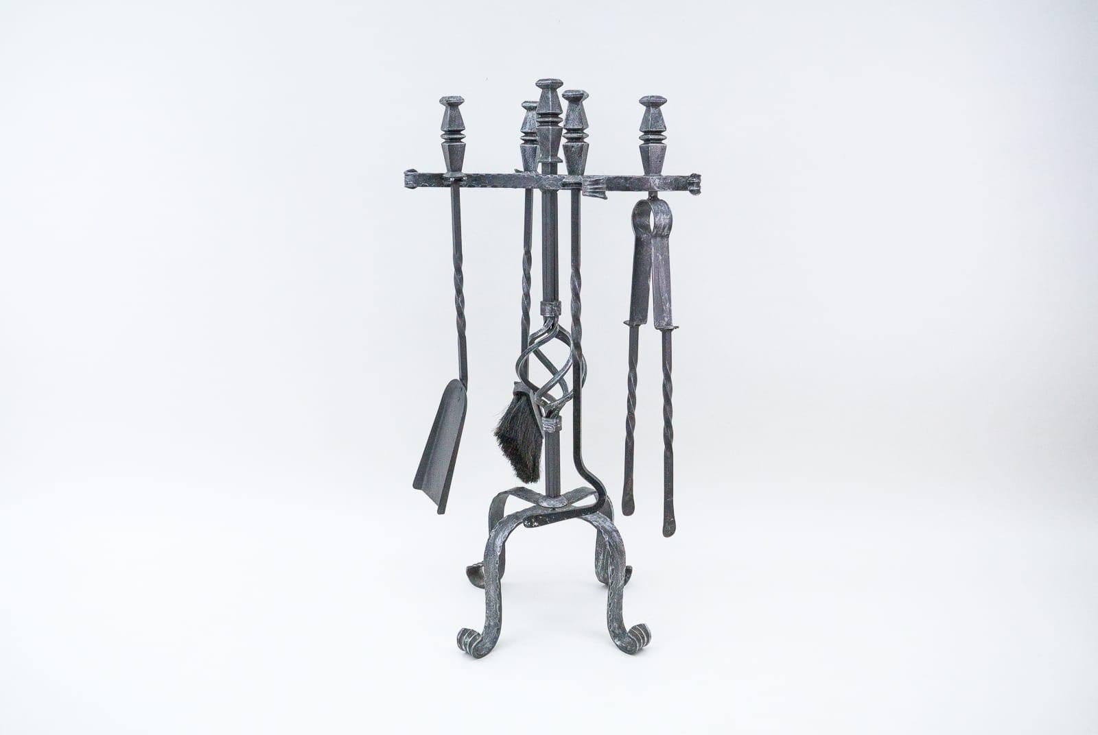 A set of four arts fire utensils on a cast iron stand.

 