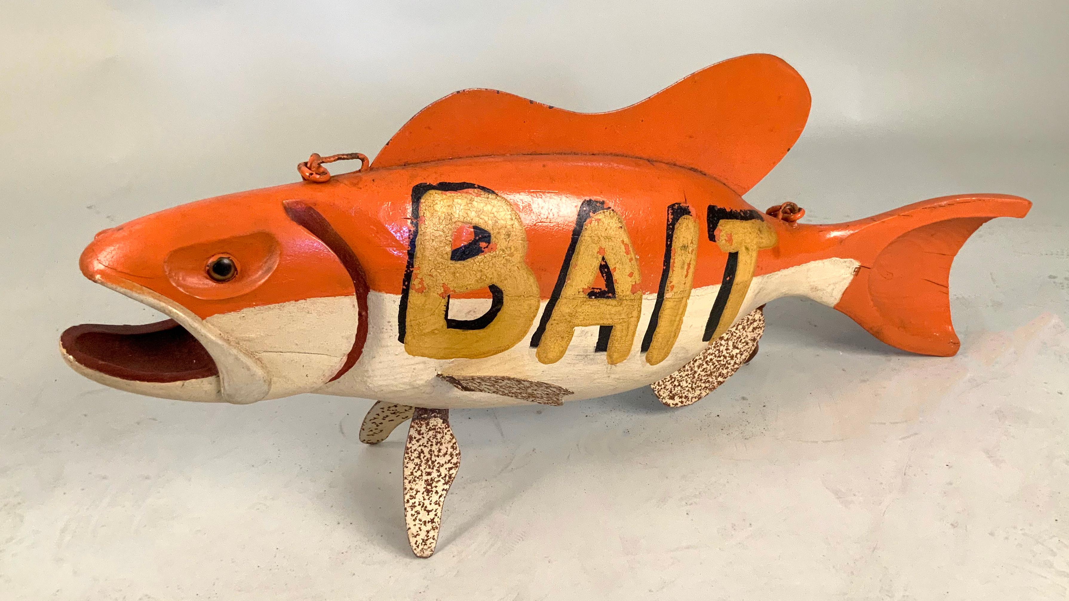 A very charming vintage trade sign for fish bait, in the form of a whole fish, with BAIT hand painted on one side, and an iron chair instact for hanging it -- painted in its original colors of orange white and with steel fins painted as well. Good
