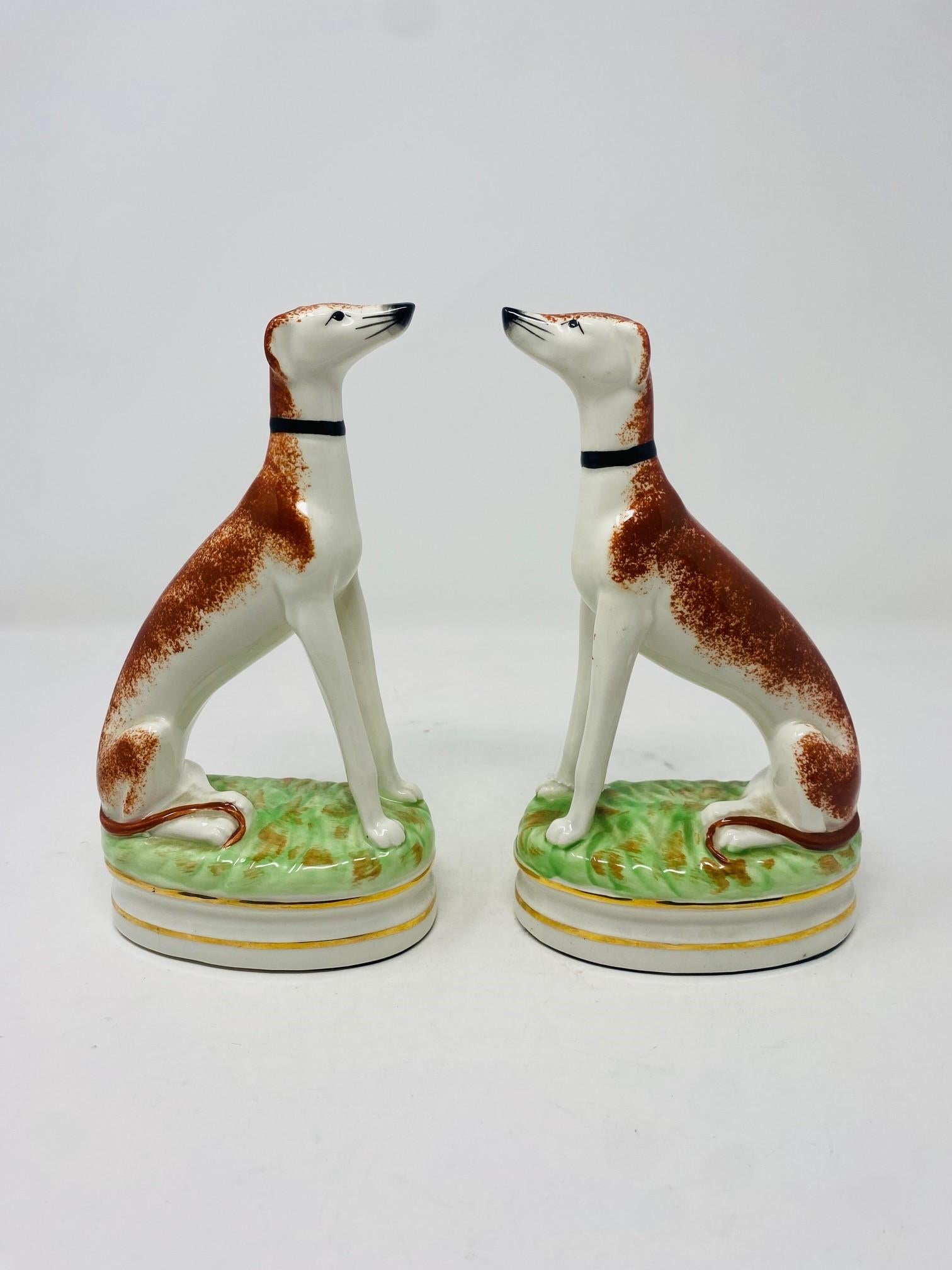 Fabuleuse paire de figurines de chiens de chasse en porcelaine Staffordshire assis sur des coussins d'herbe avec garniture dorée. Sous le pad de protection en feutre se trouve un trou que l'entreprise a fait exprès de percer pour pouvoir y placer