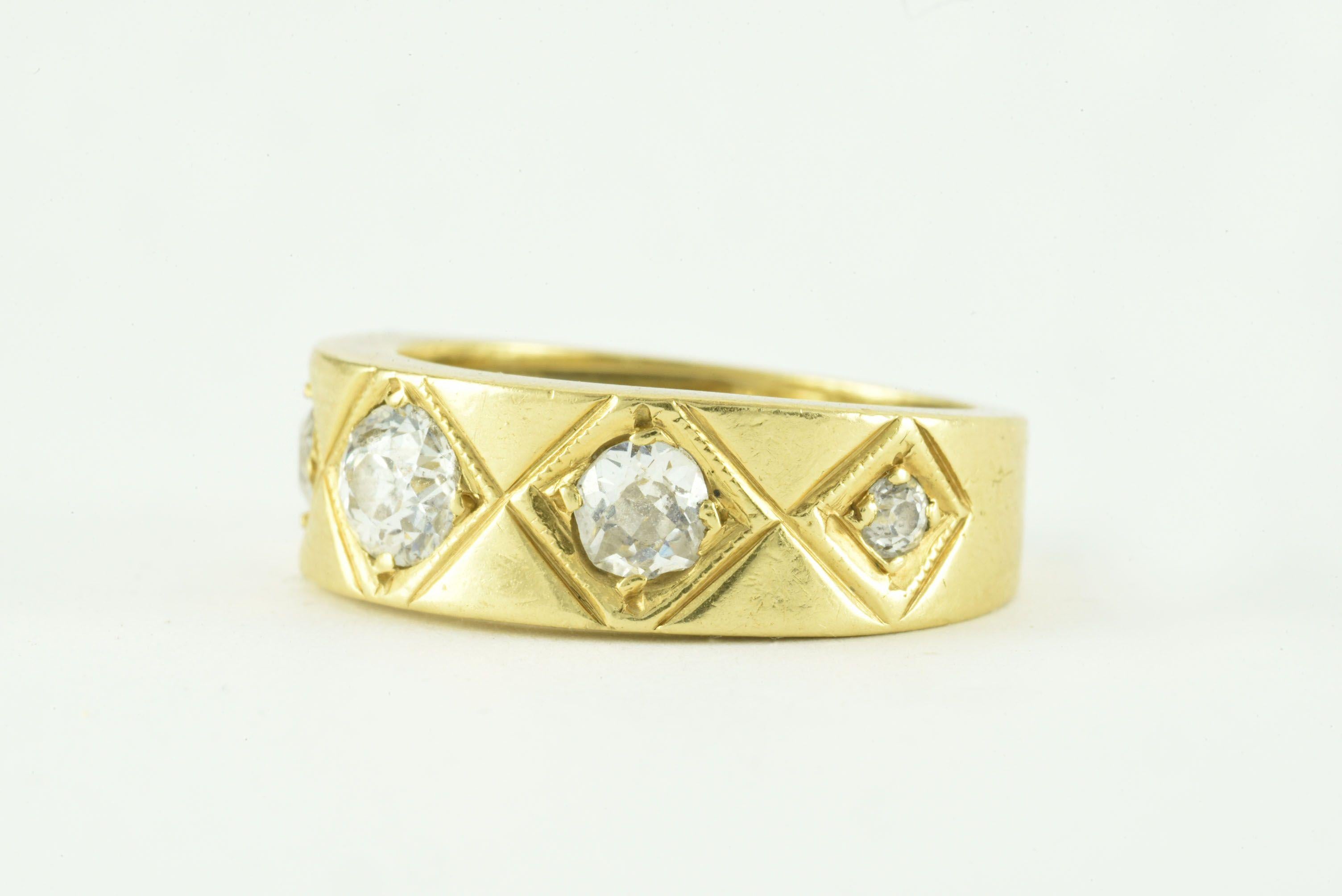 Five Old Mine cut diamonds totaling approximately 0.60 carats, H color, SI2 clarity, sparkle within a gipsy setting and framed by engraved diamond-shaped patterns and delicate milgrain atop a bold and substantial 18kt yellow gold band. 
