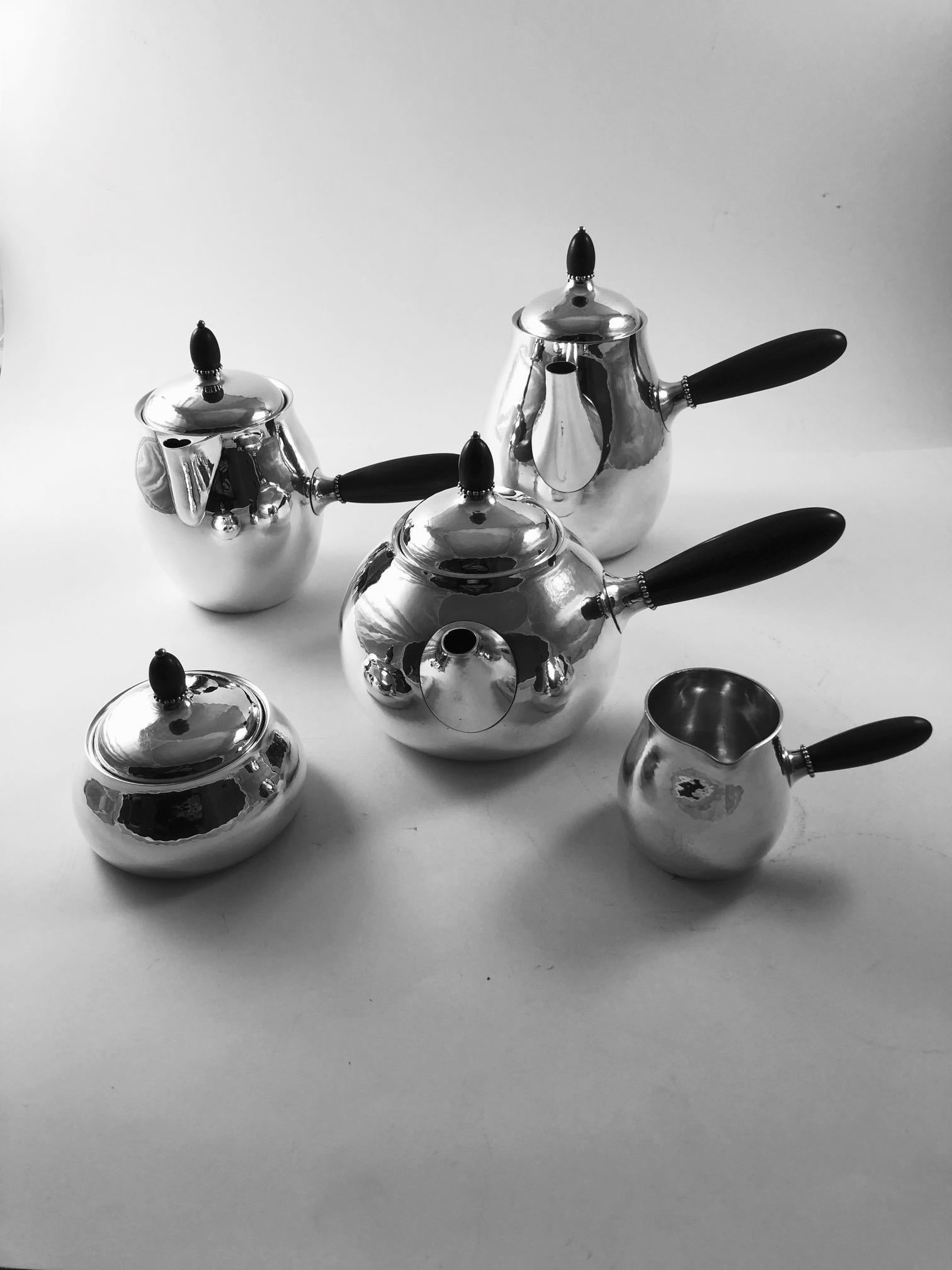 Offered at a very reasonable holiday price, a five piece Georg Jensen tea and coffee service with ebony handles.
Design #80 by Georg Jensen from circa 1906. The set is –

#80A coffee pot, 6 3/4? (17cm) in height
#80A teapot, 5 1/8