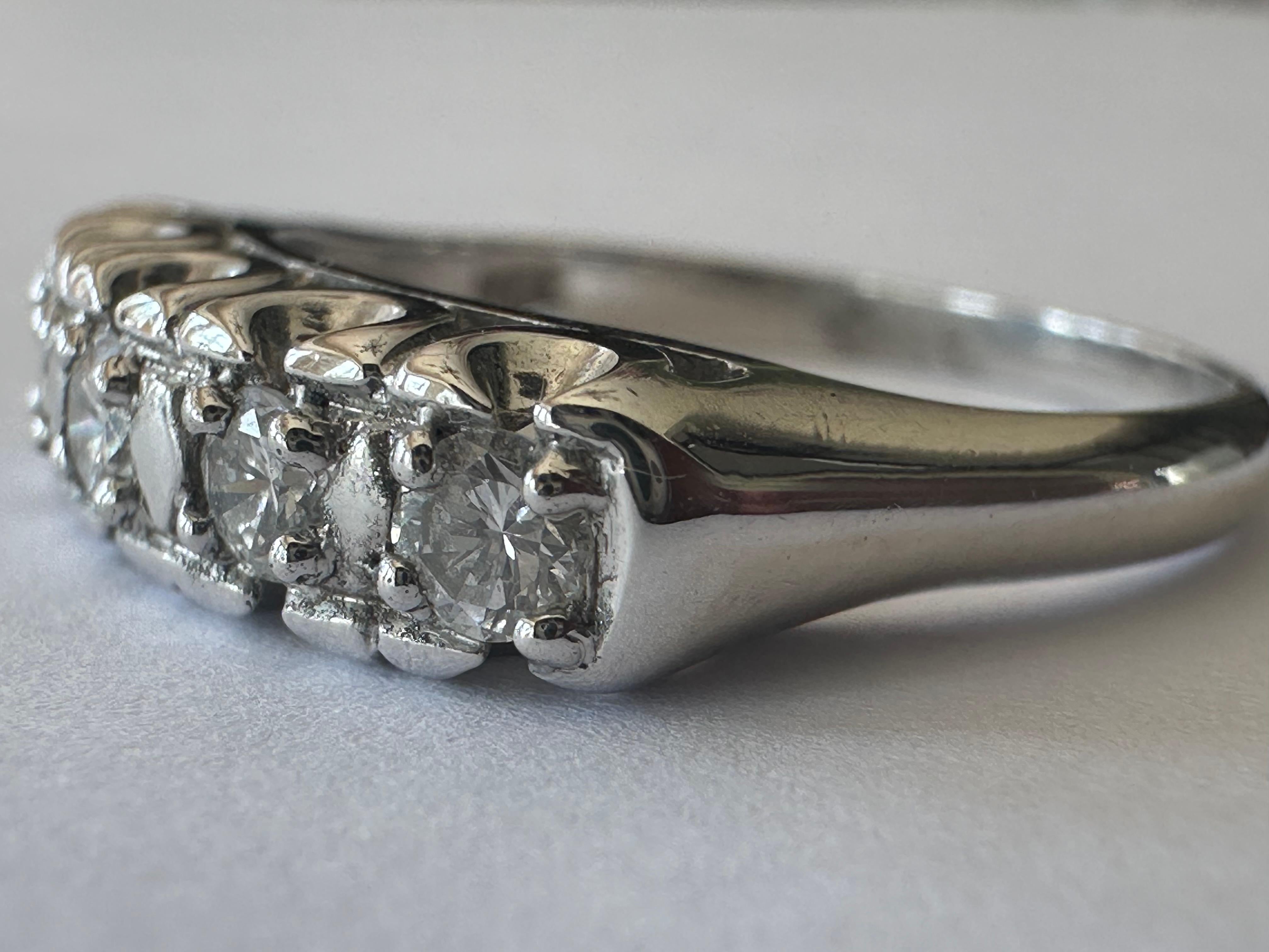 Five round brilliant-cut diamonds totaling approximately 0.50 carats F color VS clarity shimmer across the top of this classic band crafted in 14K white gold. The width of the top of the band measures 4.8mm. 
