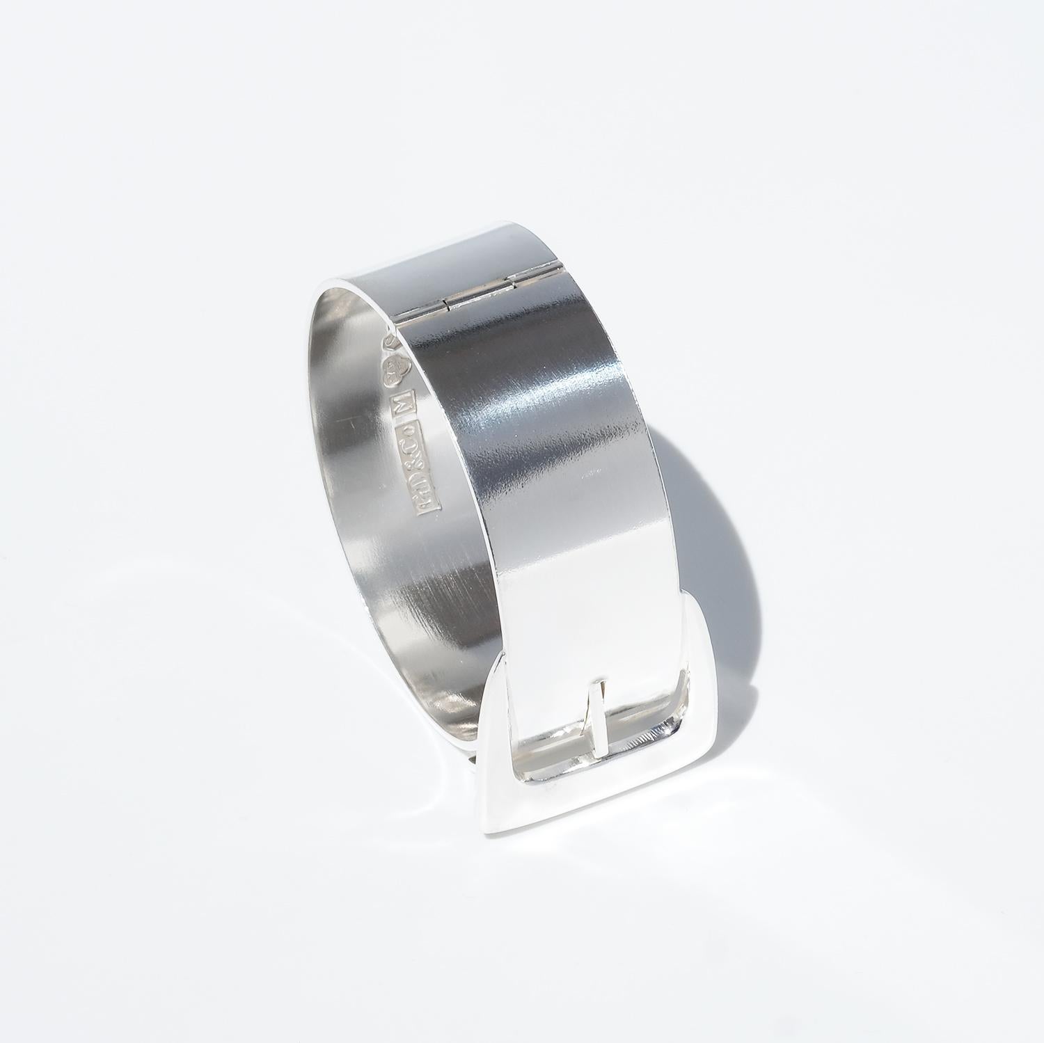 Questo bracciale in argento è stato progettato come una cintura stilizzata, con la fibbia perfettamente integrata nella parte superiore come elemento decorativo e chiusura funzionale. L'ampia fascia ha una superficie liscia e lucente che ne esalta