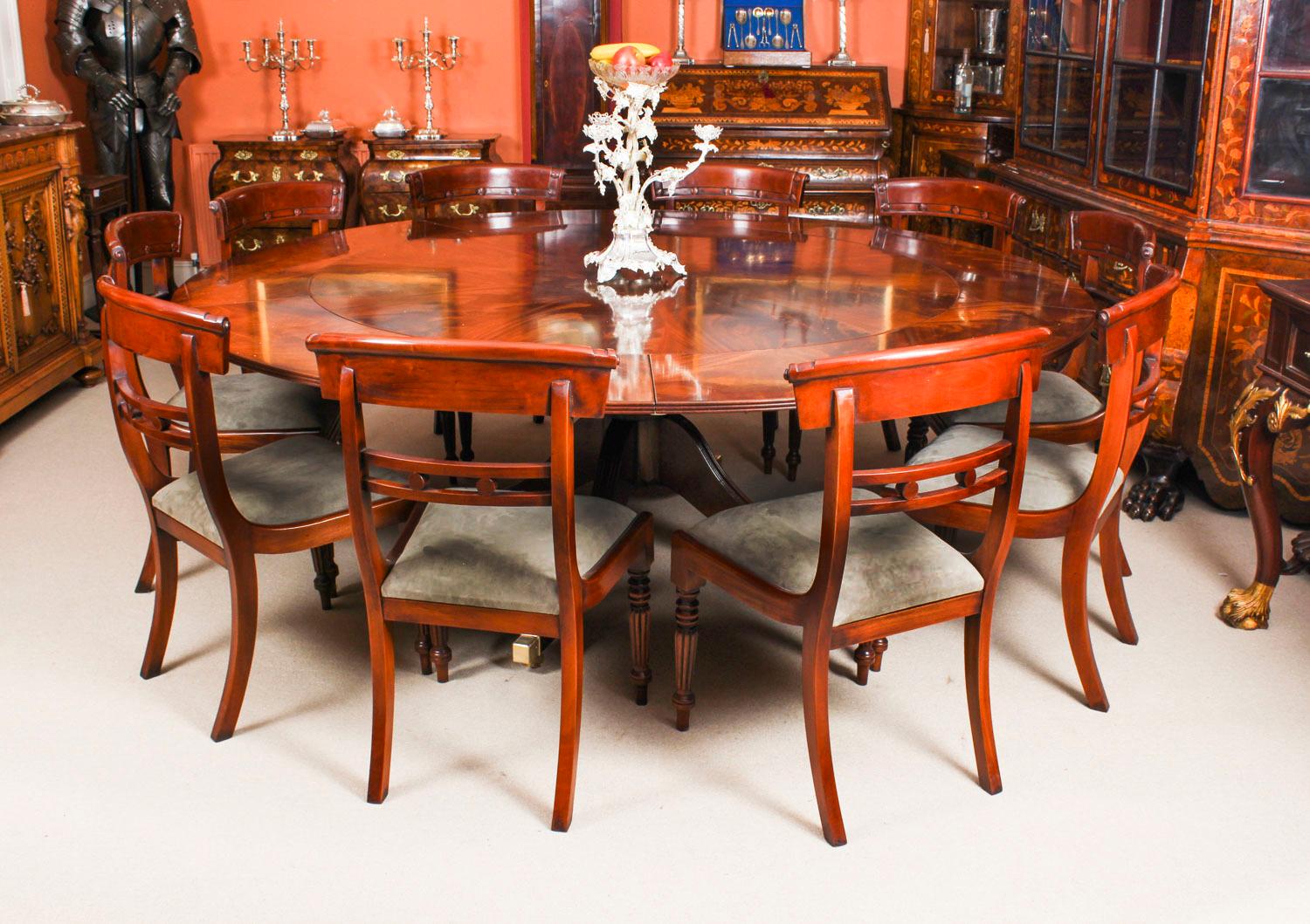 This beautiful dining set comprises a Regency Revival Jupe style flame mahogany dining table and a set of ten Regency Revival dining chairs, dating from the mid-20th century.

The table has a solid mahogany top with a fabulous flame mahogany