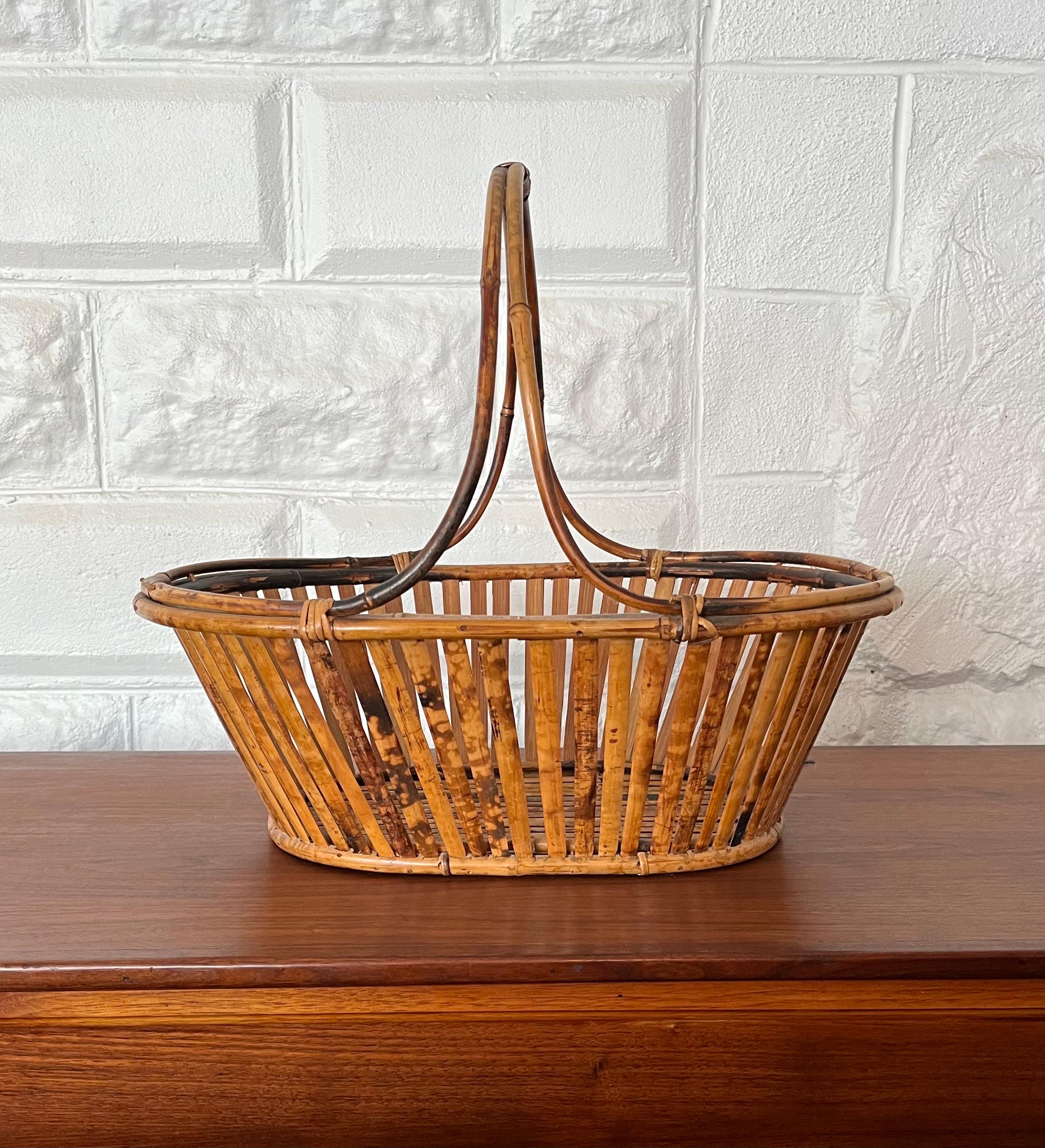 Beauty in its simplicity. Flat reed rattan basket with unique twisting rattan frame and handle. Eye meanders up and around the handle in a reverse directional manner. Simply chic.
