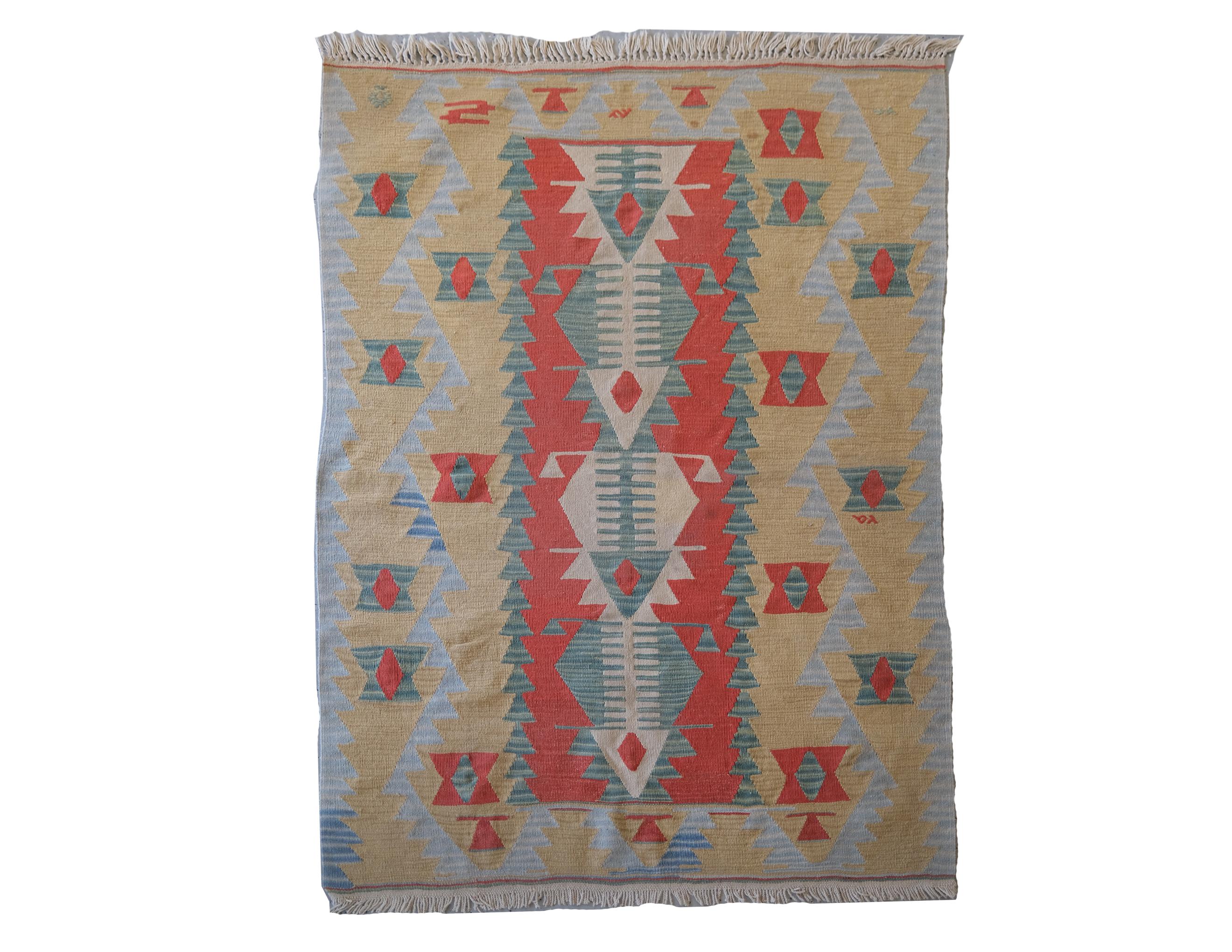 Flat-weave rug with geometric pattern of green, tan, and red.