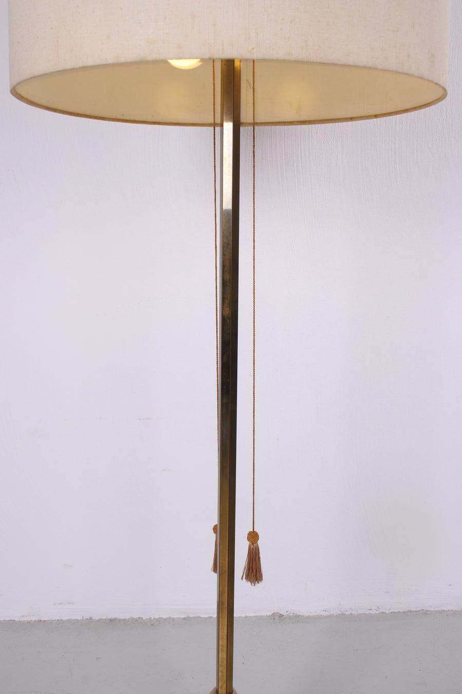 Vintage Floor Lamp with Cast Iron Base and Brass German, 1960s

Vintage floor lamp with a brass base and fabric shade. The stand consists of brass and cast iron base. The color of the fabric shade has a cream-like color. The floor lamp contains 2
