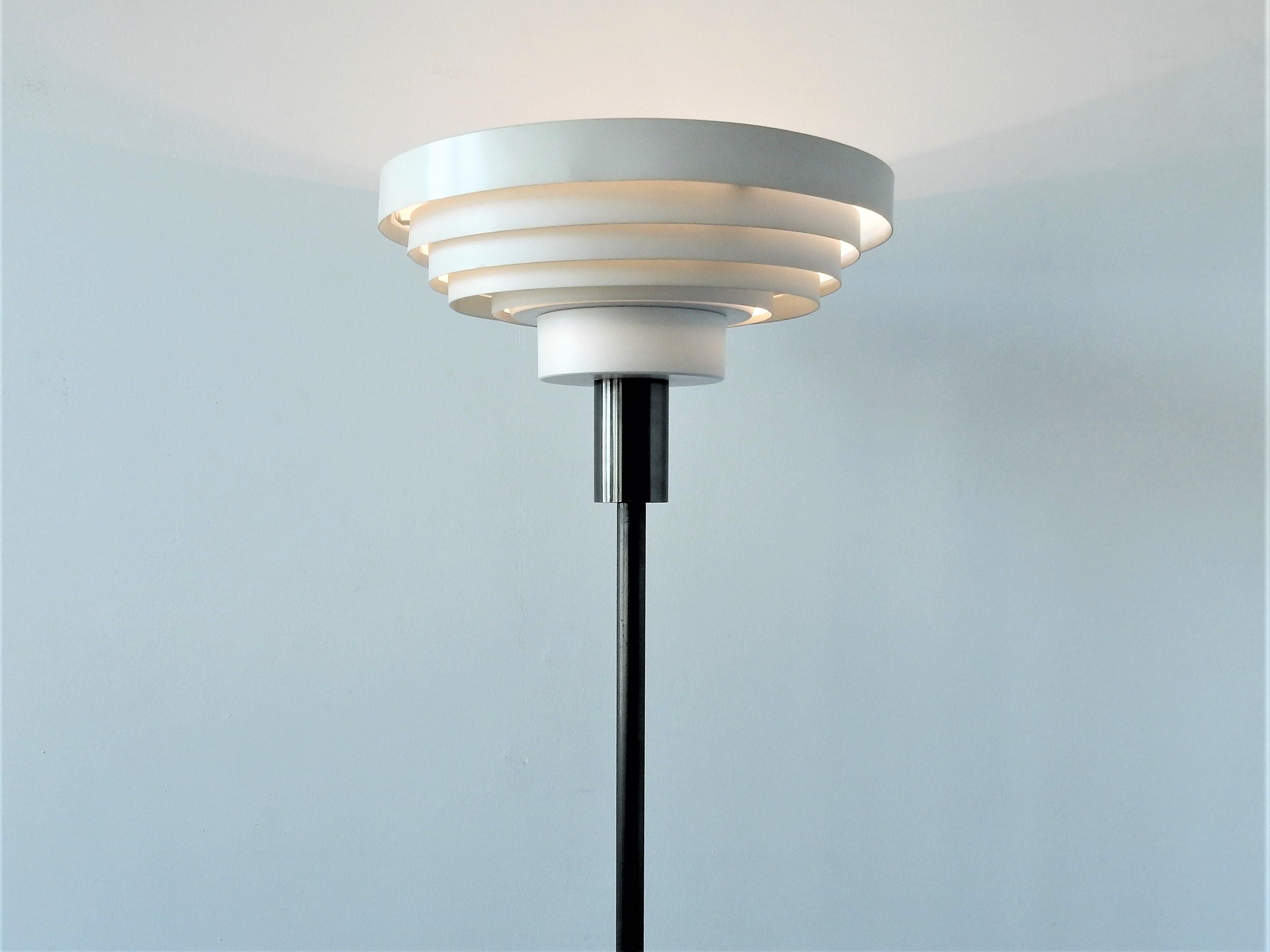 Ce lampadaire est un design haut de gamme et intemporel des années 1960. Il a une base en métal steelbronse avec des anneaux blancs comme ombre qui donne une très belle lumière directe et indirecte. La lampe est en bon état avec des signes d'âge et