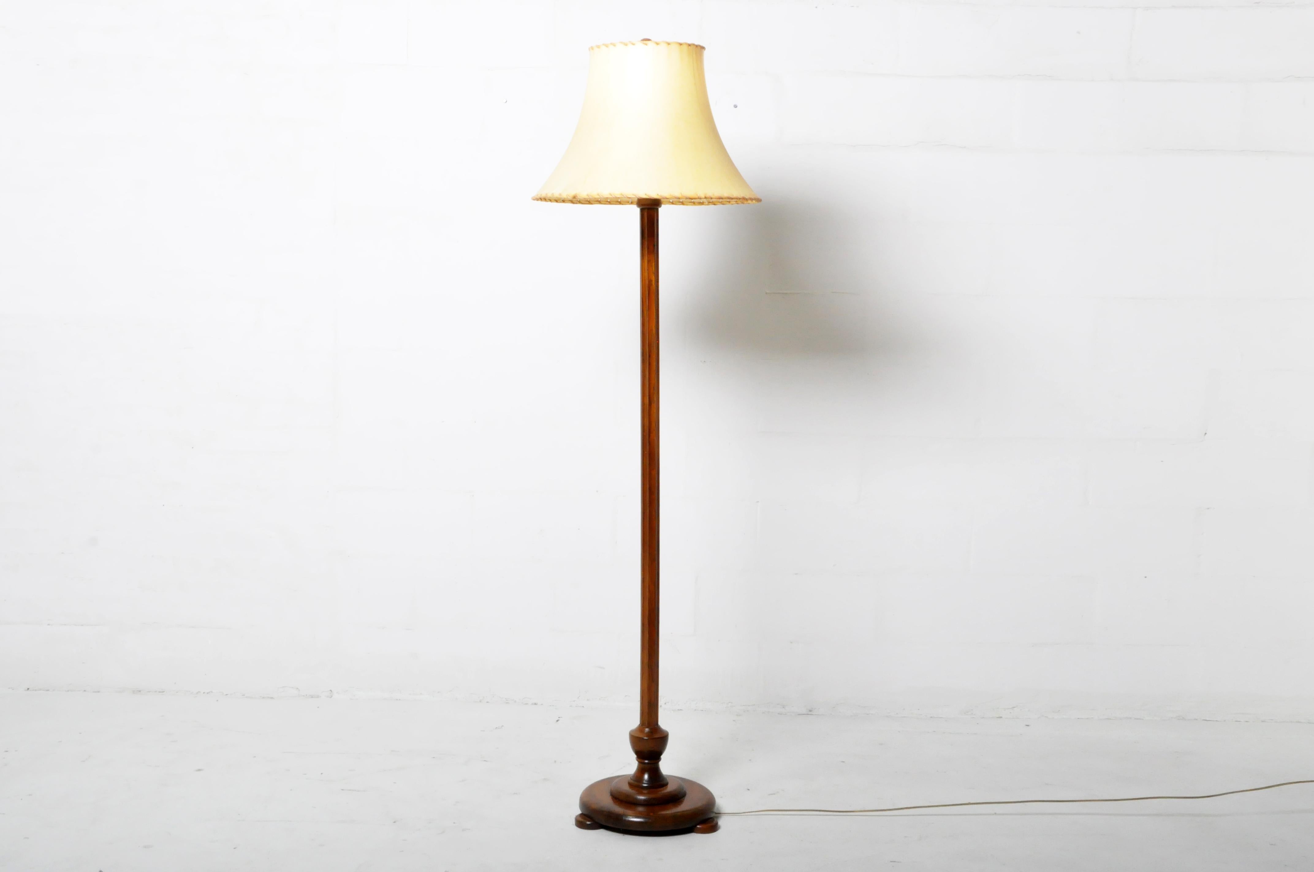 This sturdy and simple floor lamp dates to the 1920s and features a solid oak base and shaft. The shade is parchment. Wear consistent with age and use.
  