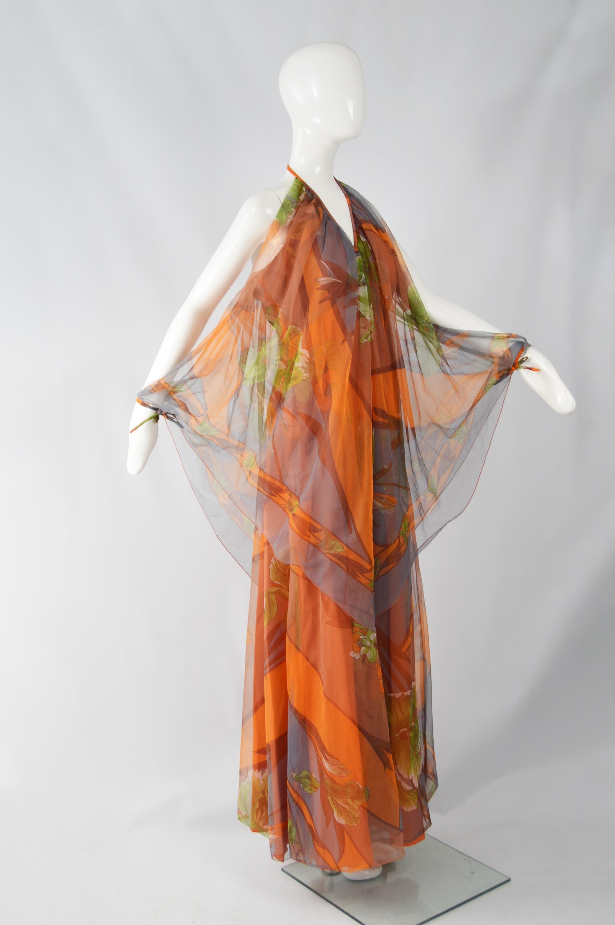 An incredibly glamorous vintage womens maxi dress from the 70s by British designer, Marian Russell. In an orange patterned, synthetic chiffon with amazing batwing style sleeves that are open at the top and tie at the wrist with a halter neck that