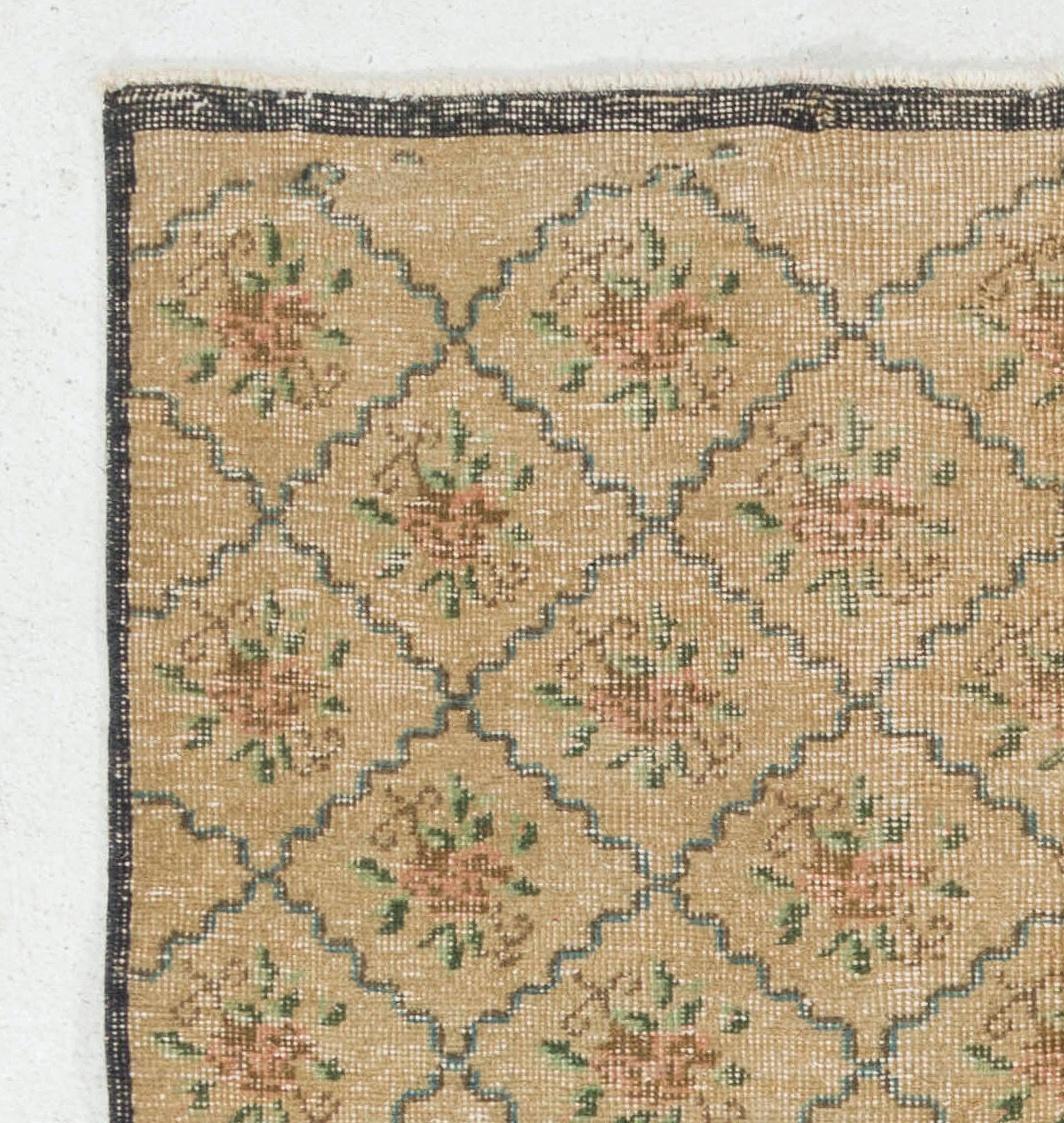A vintage Turkish village rug featuring an overall design of lattices enclosing heads of roses with petals in soft pink and delicate leaves on a sand colored field. The well-drawn curved lines of lattices in soft blue create a welcome sense of