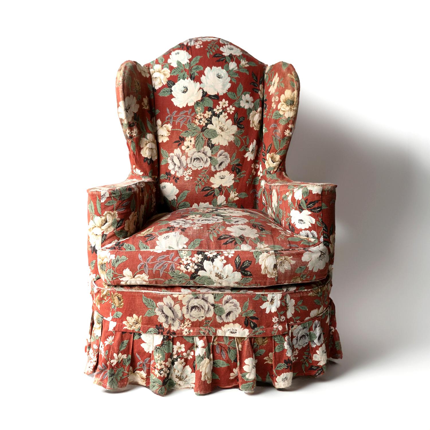VINTAGE QUEEN ANNE STYLE UPHOLSTERED WING CHAIR 
Loose burnt red cover with white rose and jasmine flowers with stylised greenery foliate designs fitted over the chair with a skirted box pleat. 

Covers a Queen Anne style, heavy and typically