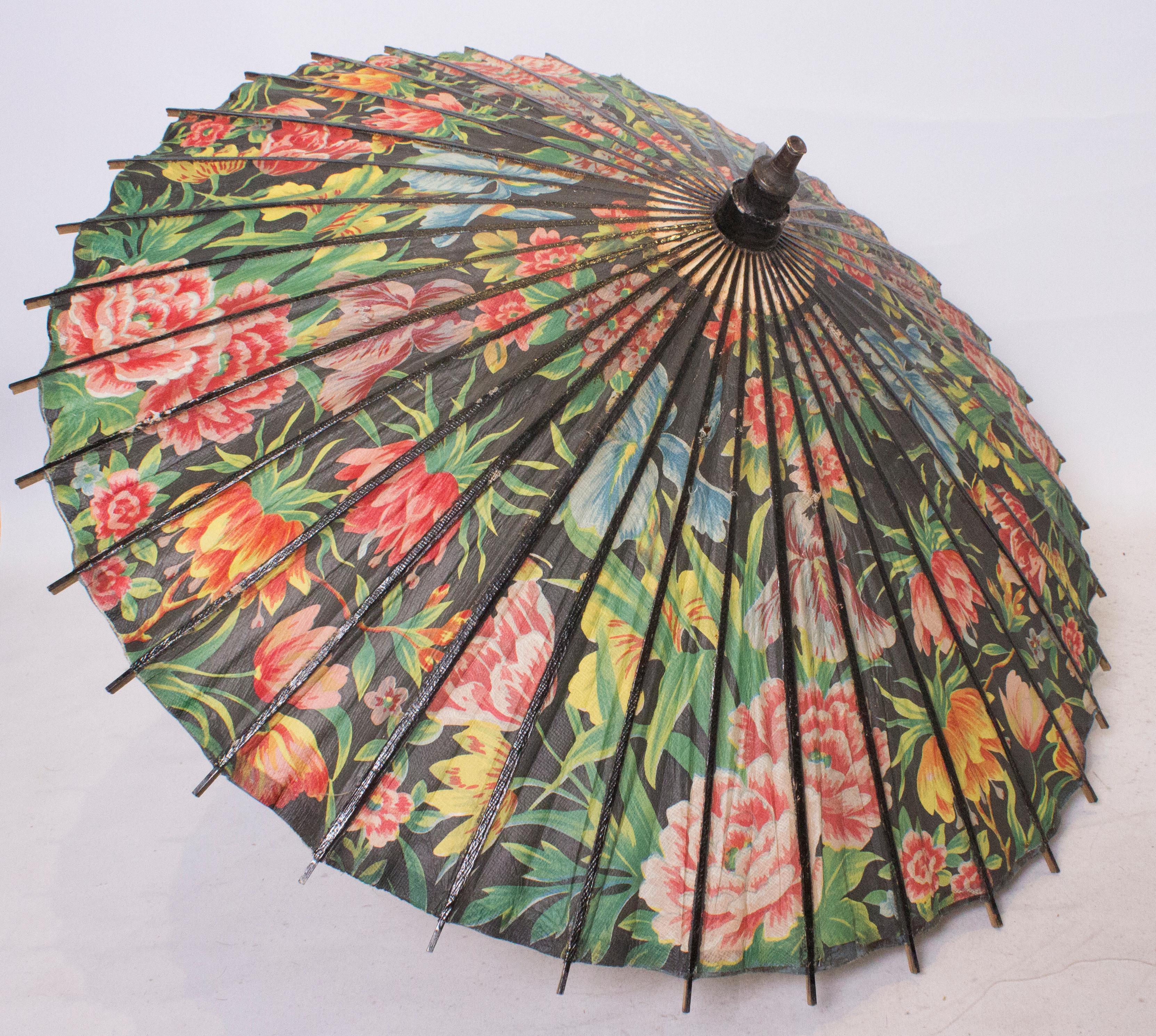 A bright and beautiful  floral parasol, great for sunny Summer days. 
The parasol has a black background with bright multicolour print and black lacquer spokes. 