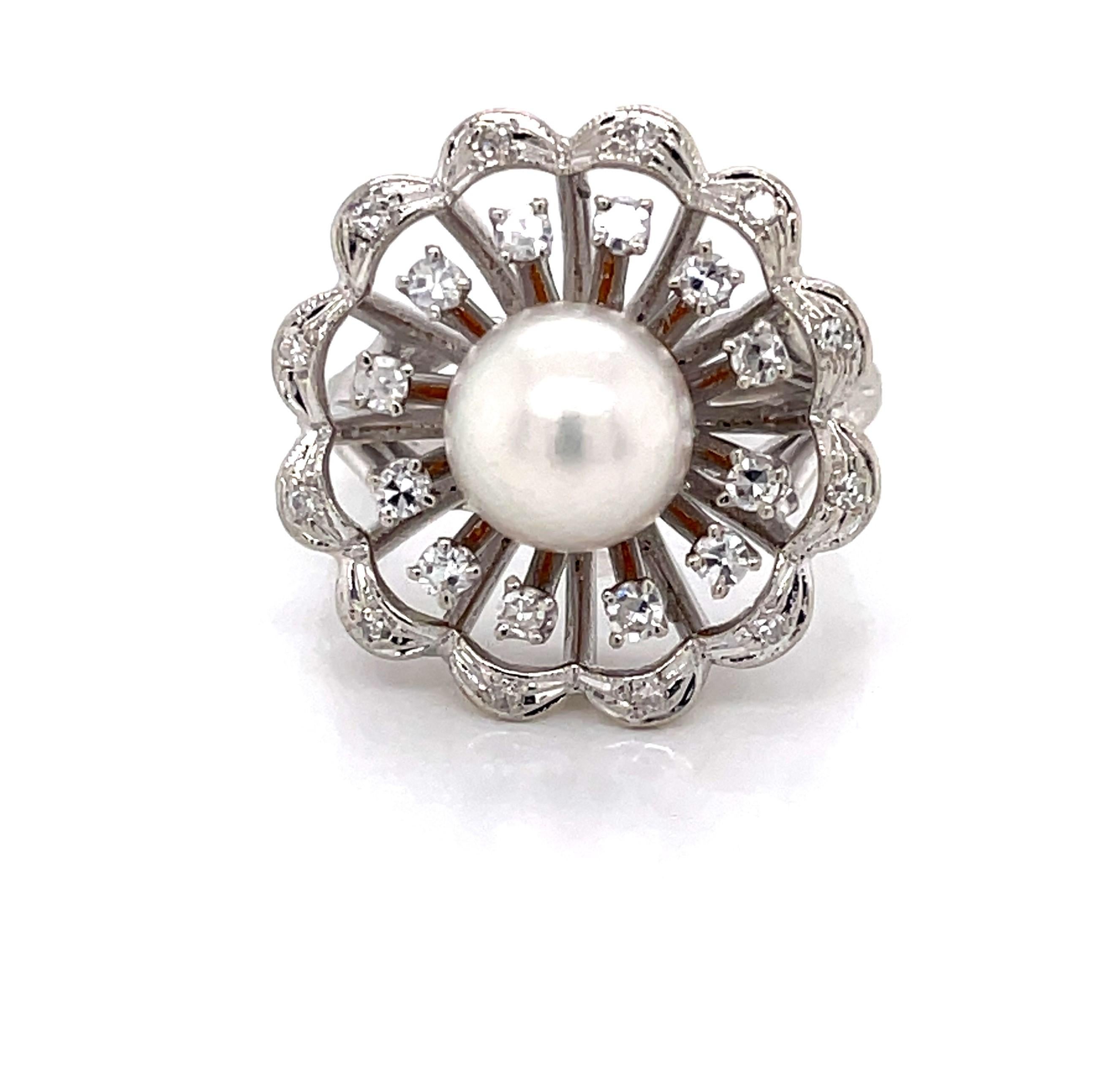 Appreciate the beautiful bloom of this vintage floral inspired pearl diamond fourteen karat 14K white gold cocktail ring. With a lacey look, continuous scalloped gold metalwork forms twelve petals, each adorned with a single faceted round diamond. 