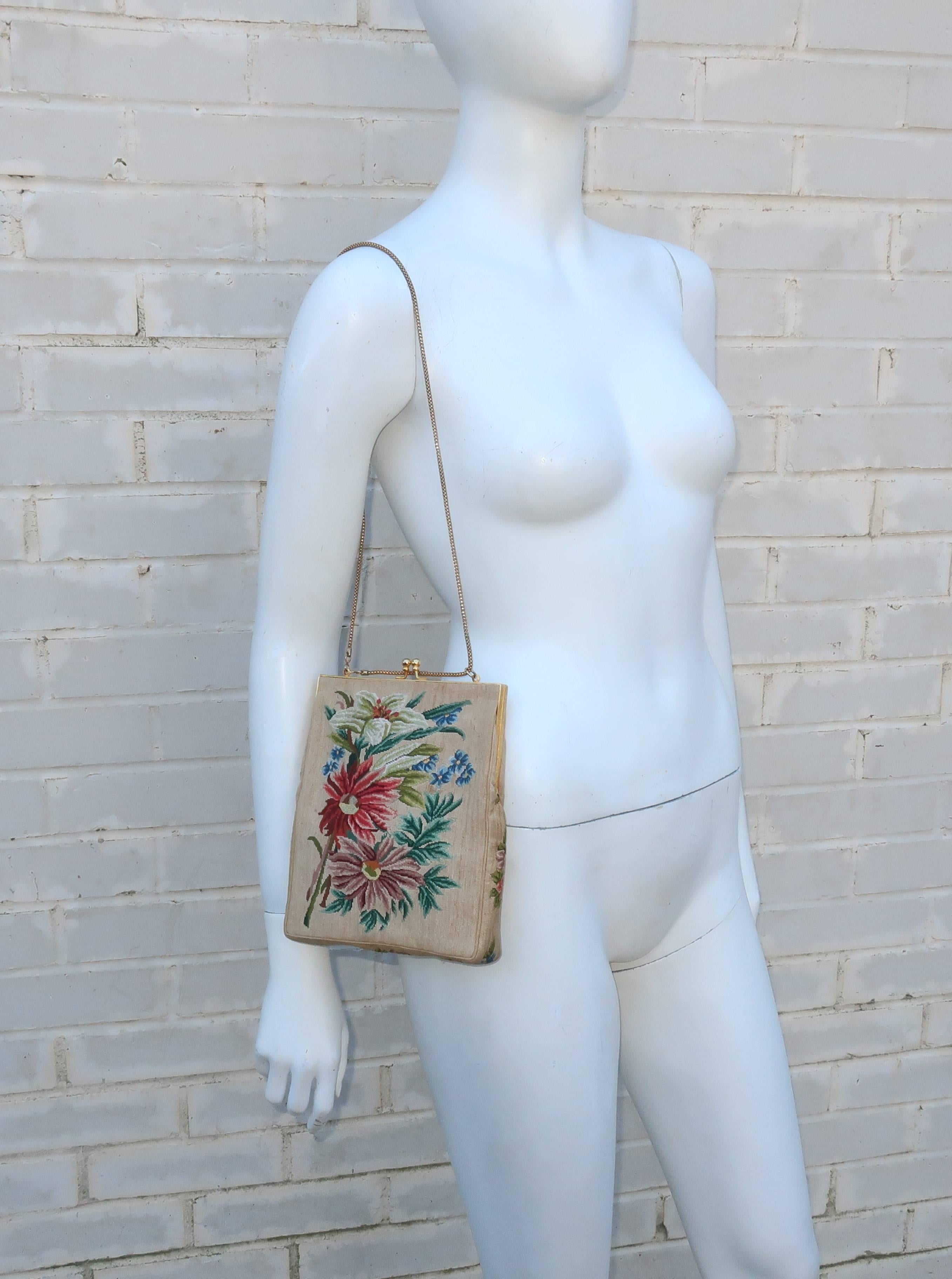 Vintage charm!  This sweet petit point handbag depicts a floral bouquet in shades of red, brown, green and blue all on a light beige background.  The gold tone metal frame is reminiscent of a trellis and the kiss lock closure opens to reveal a