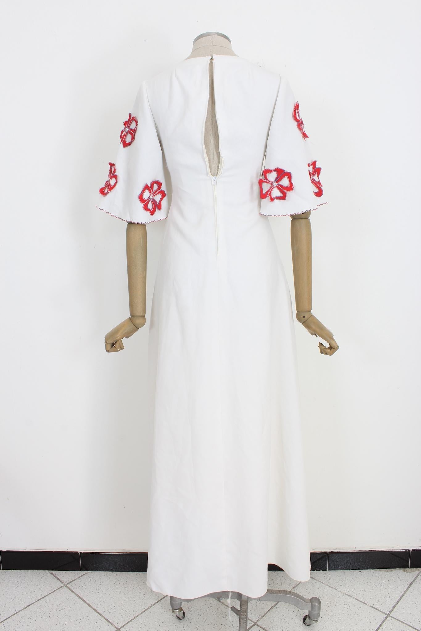 Wunderschönes 80er-Jahre-Hochzeitskleid im Vintage-Stil. Weite kurze Ärmel mit applizierten roten Blumen, die mit Perlen verziert sind. Swarovski-Applikationen auf der Brust und in der Länge, eine Organzablume in der Taille. Runder Ausschnitt,