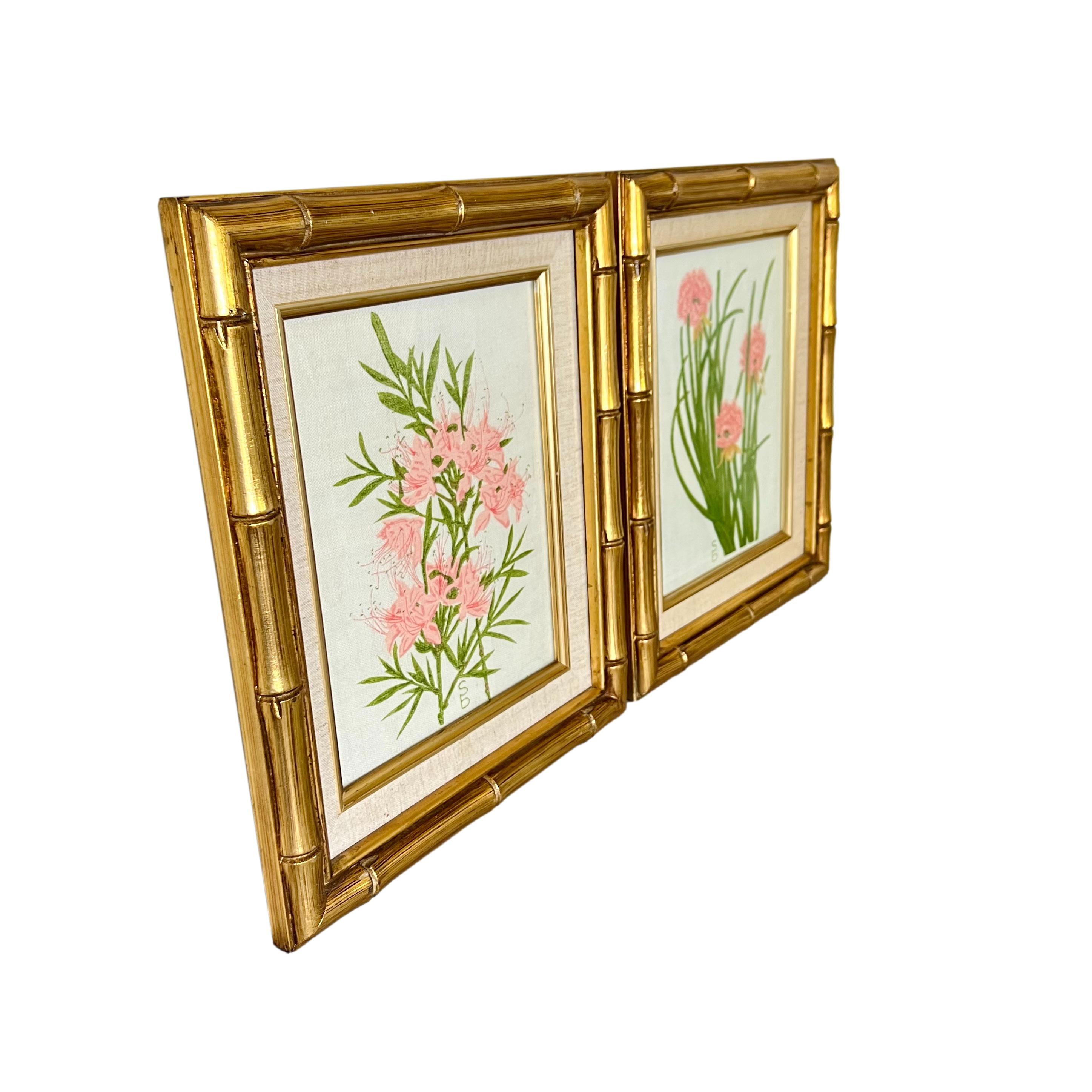 A vintage pair of framed floral silk screens. Gold antique finish faux bamboo wood frames with linen and gold metal outer borders and conservation glass.

Original designs by Sydney Bagshaw, hand printed in St. Lucia on locally sourced