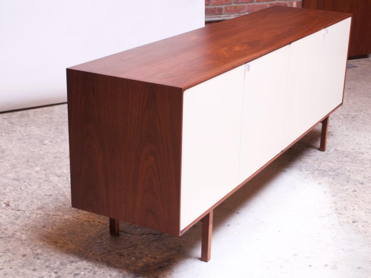 Credenza / cabinet (Model #541, circa 1952) designed by Florence Knoll for Knoll Associates composed of a walnut frame and legs with original off-white lacquered walnut doors and chrome pulls. Legs feature a unique vertical ply line detail.
Four
