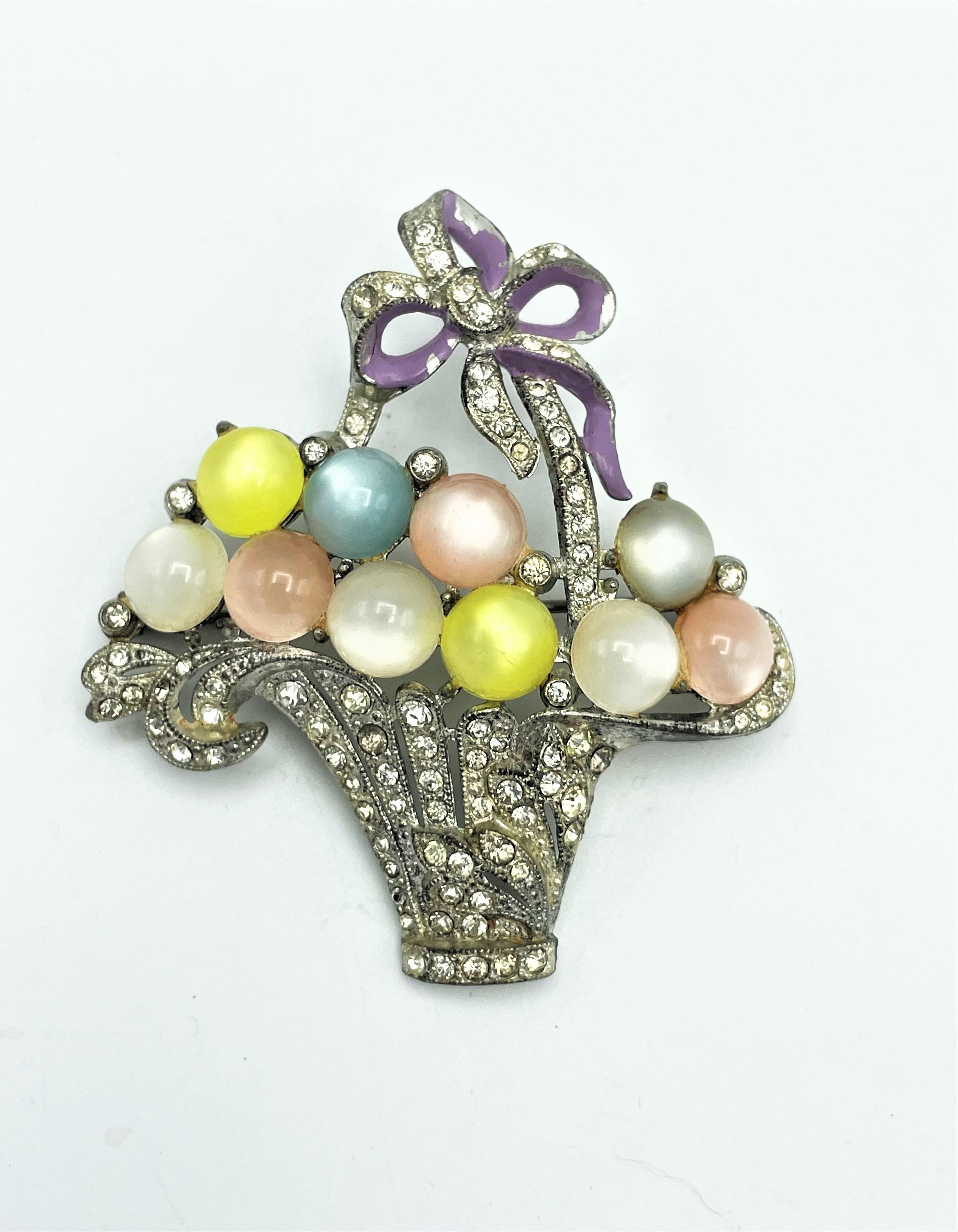 Vintage flower basket brooch cast in rhodium plated metal and set with many small rhinestones and simulated moonstones . Bow bottom enameled. Book piece!
Measurement: High 6 cm, Wide 7 cm, 10 pastel glass stones 1 cm in diameter. USA late 1930s.