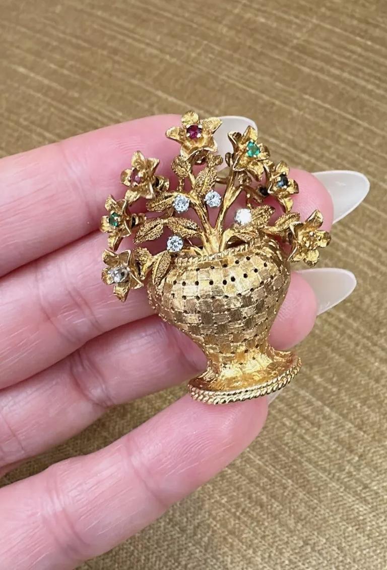 Vintage Flower Basket Brooch with Diamonds in 18k Yellow Gold 

Vintage Basket Brooch features a Woven textured basket with 7 Flowers that turn and move with gemstone centers including Sapphire, Emerald, and Ruby along with 5 Round Brilliant