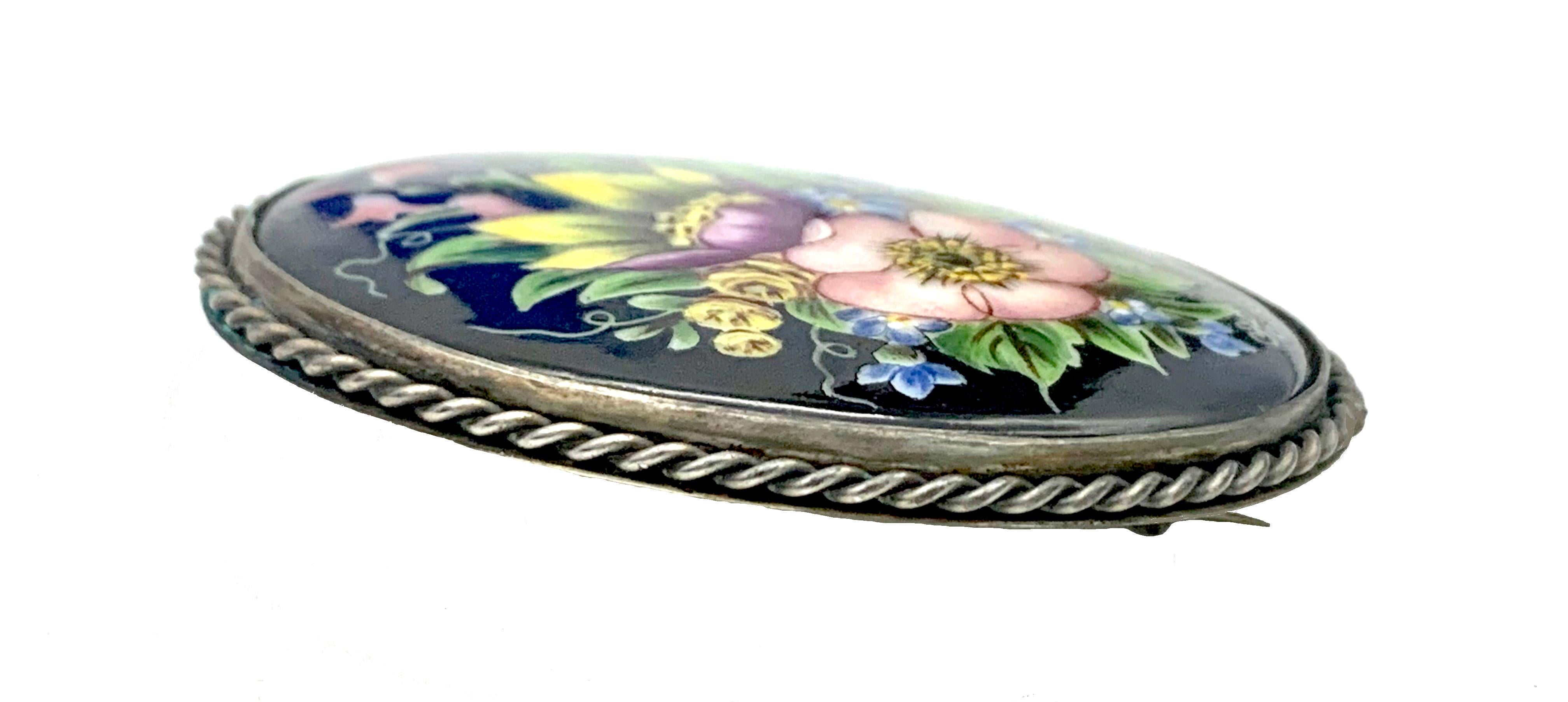 This oval porcelain miniature of a flamboyant flower arrangement on a black background is mounted in a silver brooch decorated with twisted silver wire.
The reverse of the brooch is fully signed 'C.Hopp', and impressed with Swedish silver