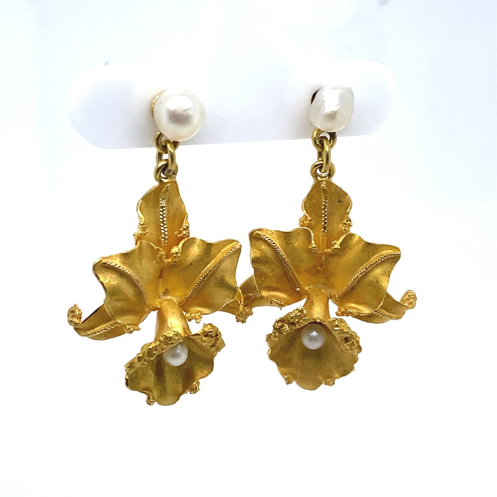 Ein Paar Blumenperlen-Ohrringe aus 14 Karat Gelbgold.

Dieses verspielte, vom Jugendstil inspirierte Paar Ohrringe aus 14-karätigem Gelbgold stellt ein Paar Stiefmütterchen dar, die von Barockperlen mit einem Durchmesser von jeweils 4 mm an Stift-
