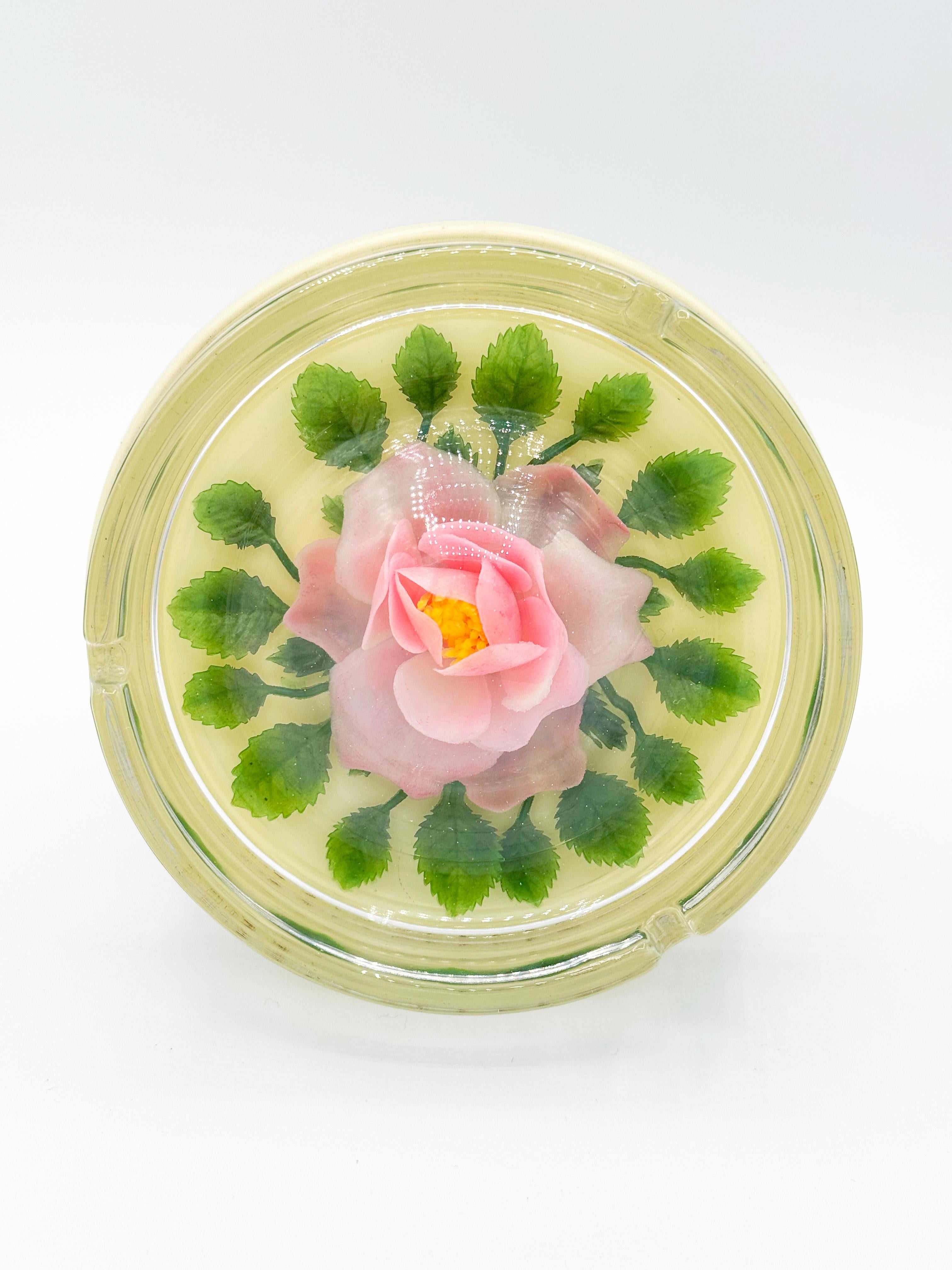Vintage ashtray, crafted in Japan during the 1960s. It features a beautifully encapsulated pink rose, offering a delicate and timeless aesthetic. The lifelike faux flower is showcased inside a clear dome, adding an ethereal element that captures