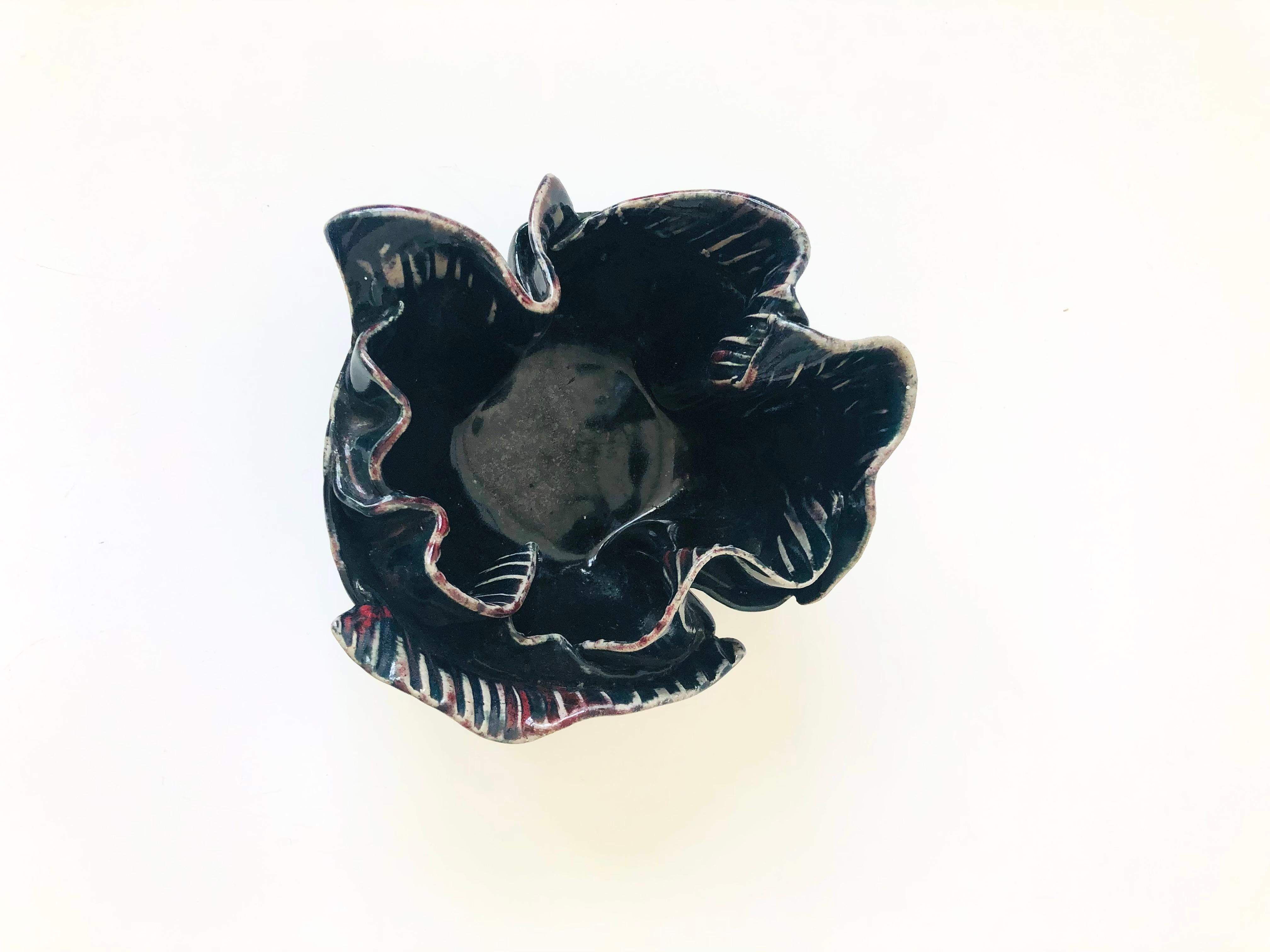 A beautiful vintage studio pottery bowl in the shape of a flower. Lovely detailing formed into the pottery to create the petals. Finished in a glossy dark glaze. Signed by the artist, Olga, on the base.
  