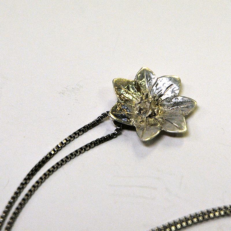 Lovely flower silver necklace made by Bronsil AB in Köping, Sweden, 1970s. The pendant has shape as a water lily with seven petals. Marked: SGP 925.
Size: Total length including the chain (double) about 22 cm. Measures: Pendant 2.3 cm D x 0.3 cm D.