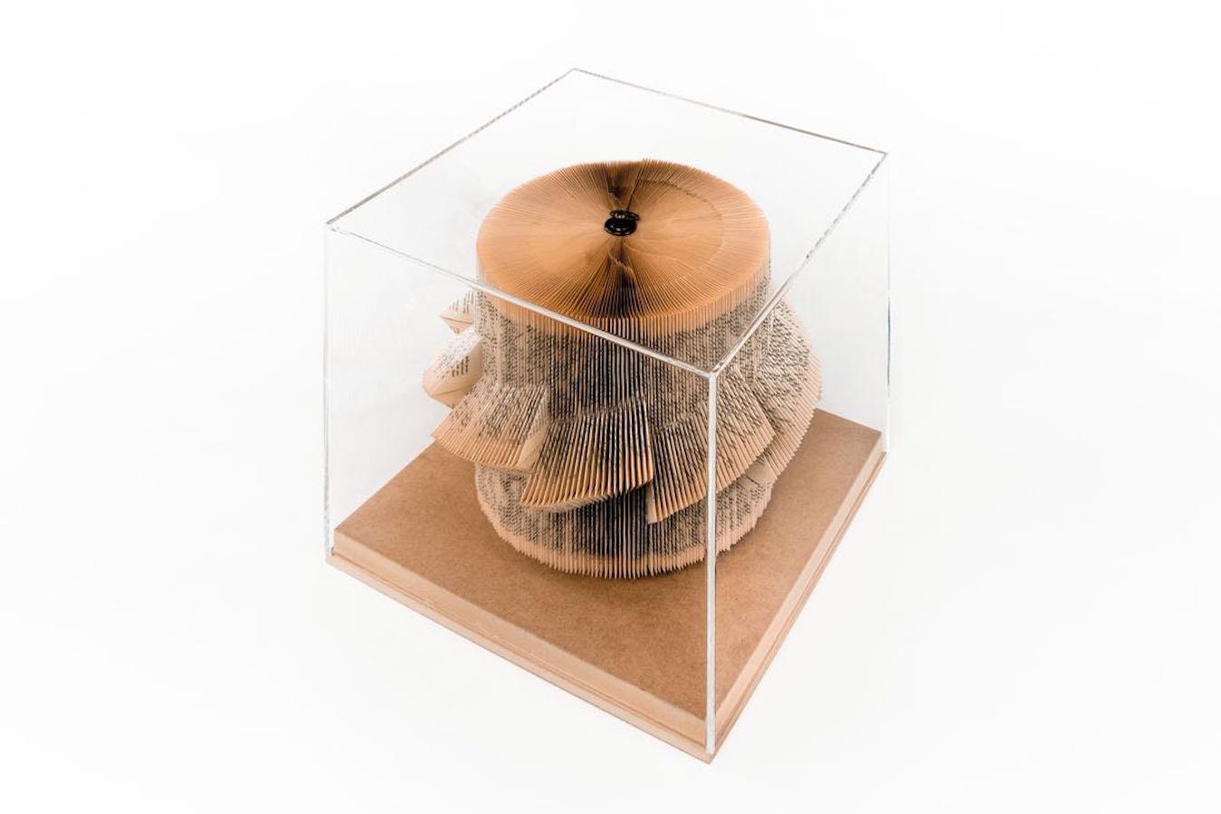 Contemporary Italian hand folded pages of vintage book creates unique and very decorative sculpture.
The sculpture is round and folded in a sail shape. There is a brass ring atop the sculpture.
Placed under plexi box on wooden stand.
 