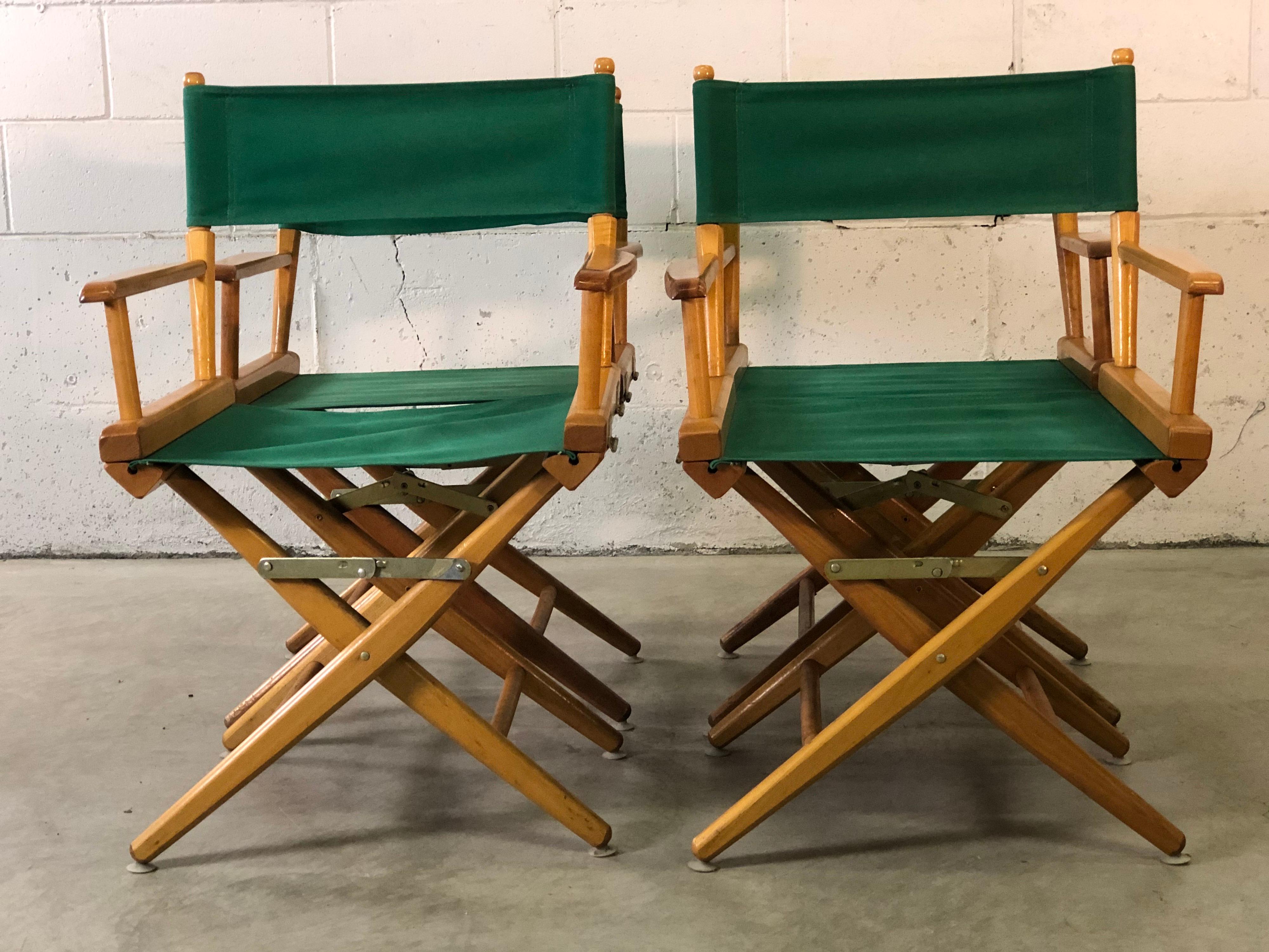 Vintage 1980s set of 4 directors chairs with wood frames and green canvas fabric. All four chairs fold up for storage and have a bright green fabric. Marked under the arm. Made by Telescope.