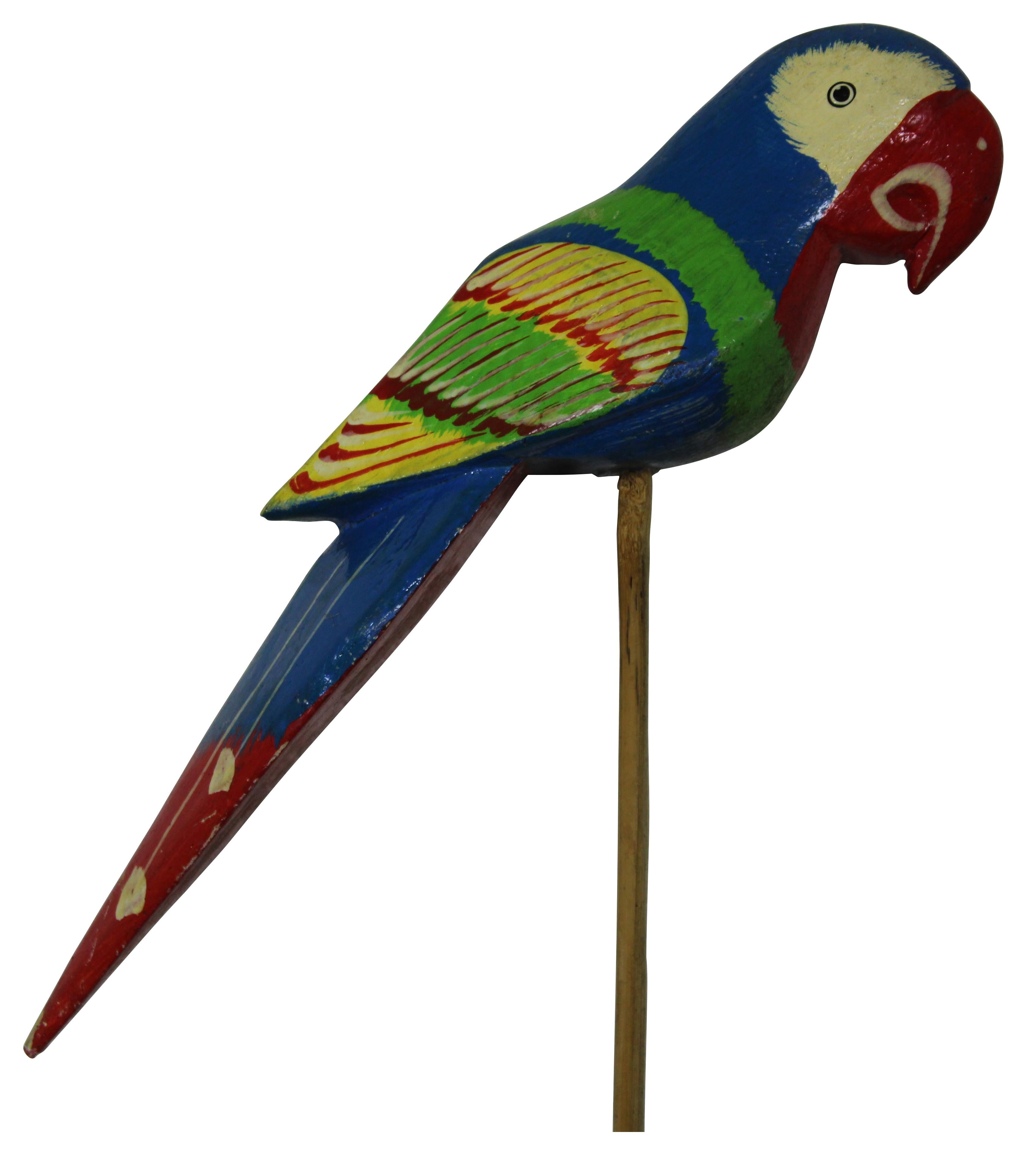 Vintage brightly painted carved wood figurine of a parrot, perched on a dowel rod.