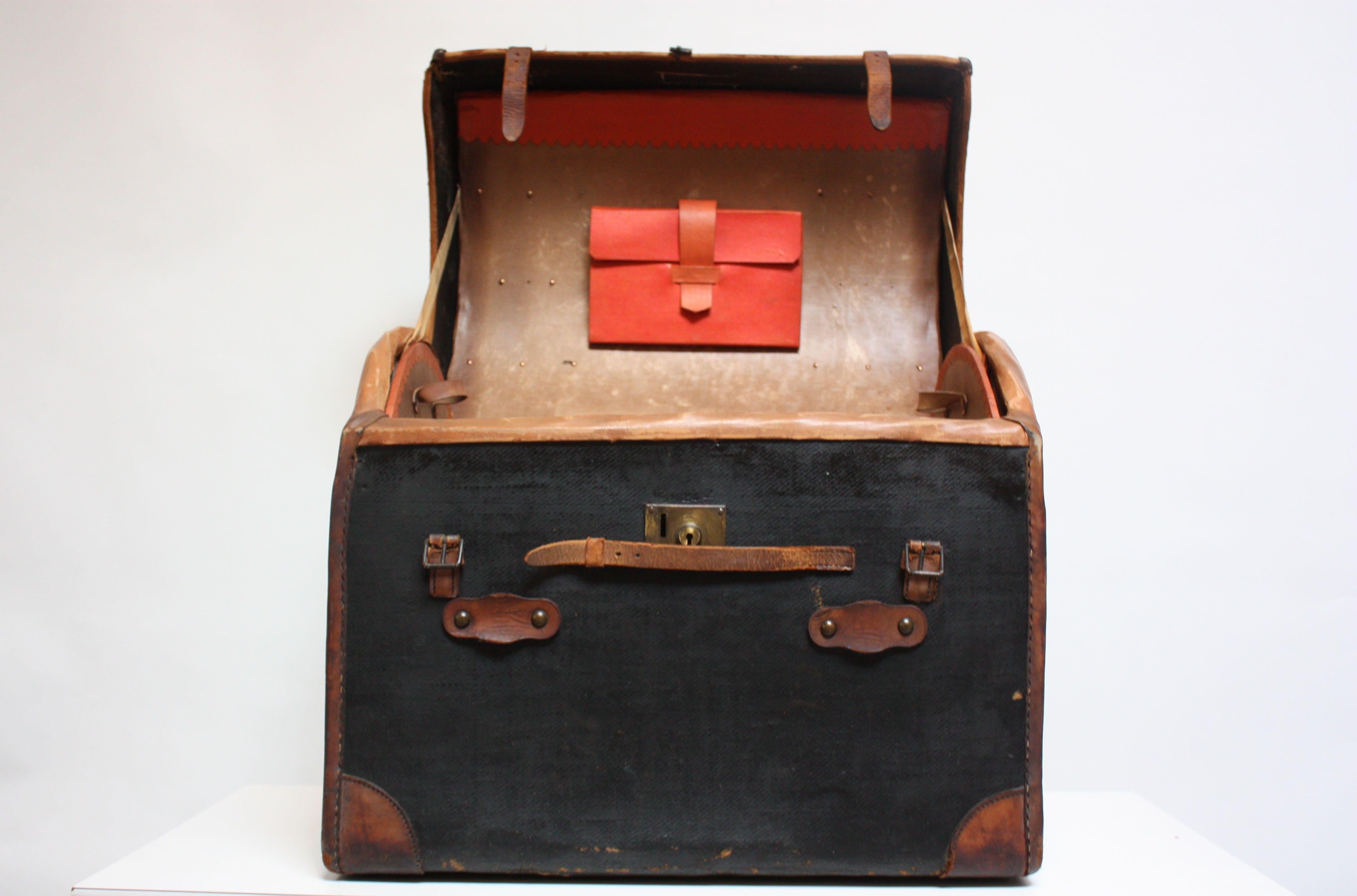 Unique steamer trunk (circa 1920s) composed of a heavy black canvas exterior with leather straps / accents and brass hardware. 
The interior red canvas 'folder' with leather clasp can accommodate pictures / documents. There is an interior tray,