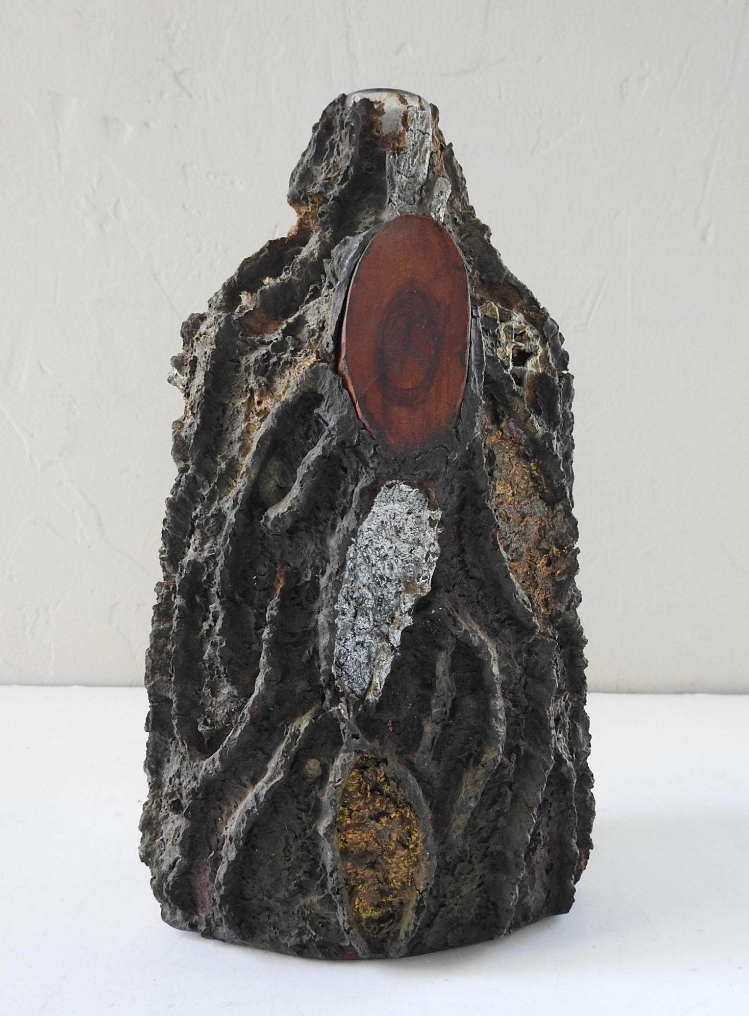 Vintage bottle covered in wood and textured putty to resemble bark.  Wire mesh with wood pieces and shaped putty in dark brown over bottle,  accented with silver and gold paint.  Overall crazing, some losses.