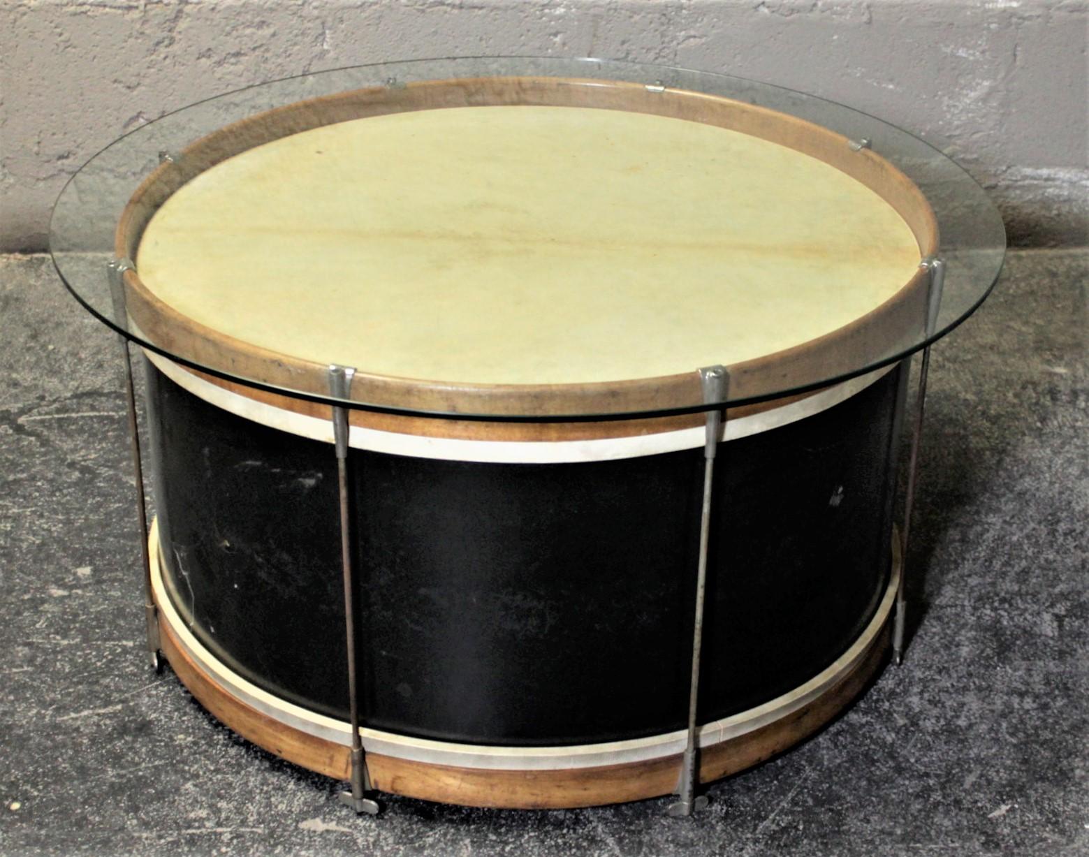 This novel Folk Art glass topped drum coffee or cocktail table has no maker's tag on it, but it is presumed to have been made in the United States in circa 1940s. This vintage bass drum has natural wood rims a painted wood body and chrome lugs. The