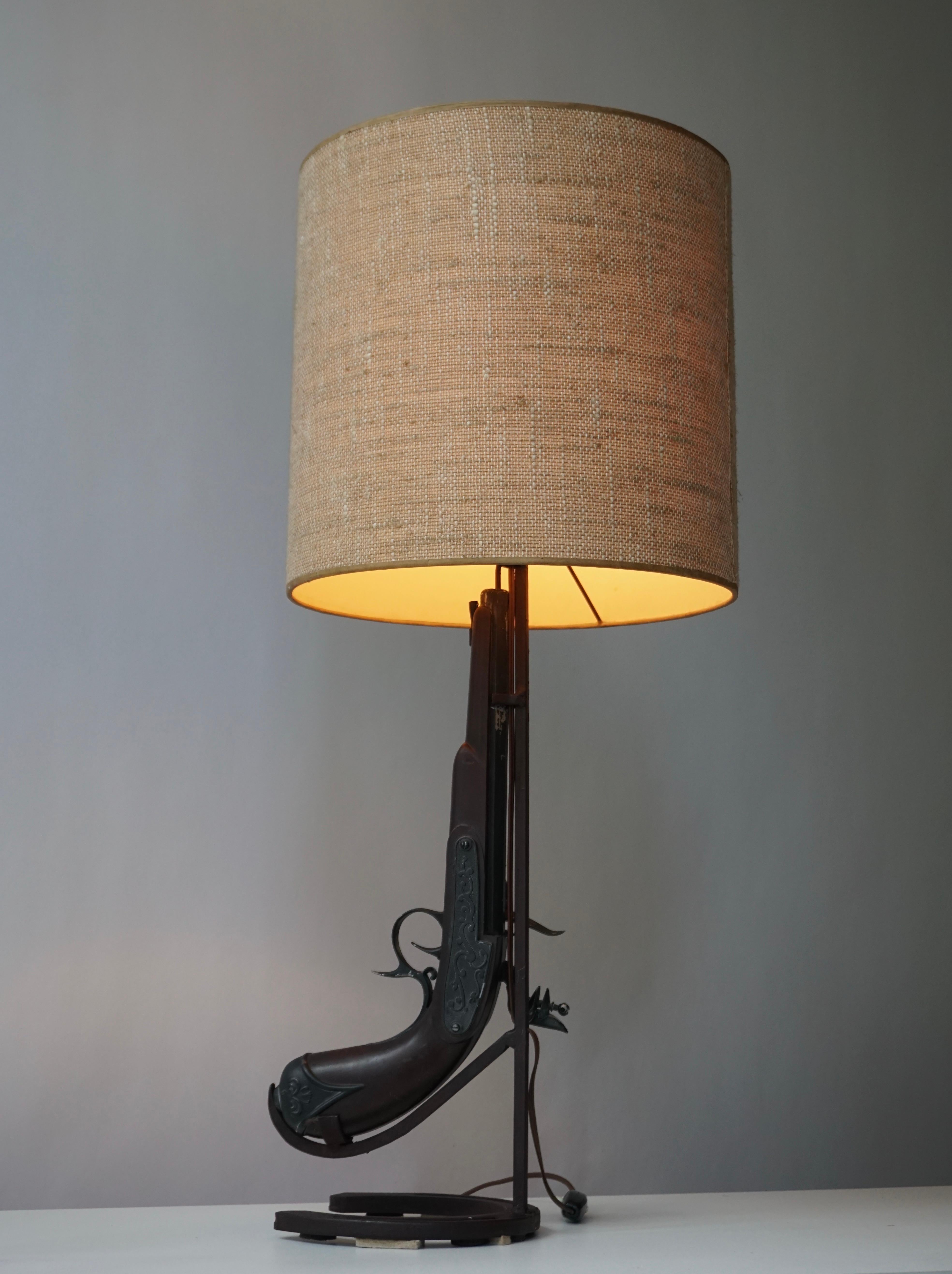 Lampe de table Vintage Folk Art fabriquée à la main en forme de fusil, en bois et en fer forgé, avec un fer à cheval antique monté comme guidon.

Mesures : Hauteur 70 cm.
Diamètre 30 cm.