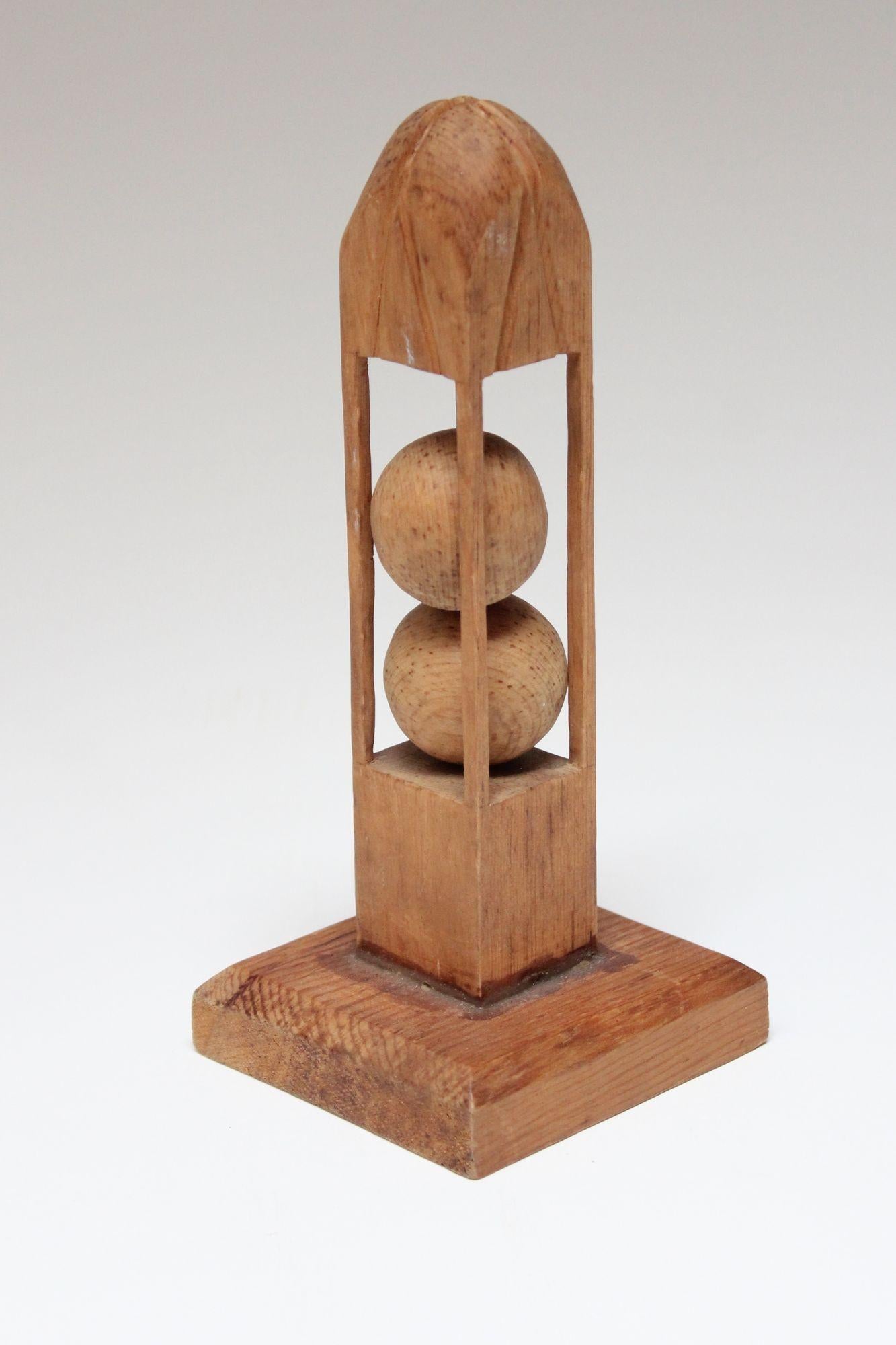 Folk Art whimsy 'ball in cage' obelisk sculpture whittled from one continuous piece of wood and adhered to a wooden plinth base, circa 1940s. The carved supports holding the two balls in place lack refinement, enhancing the crude / outsider style of