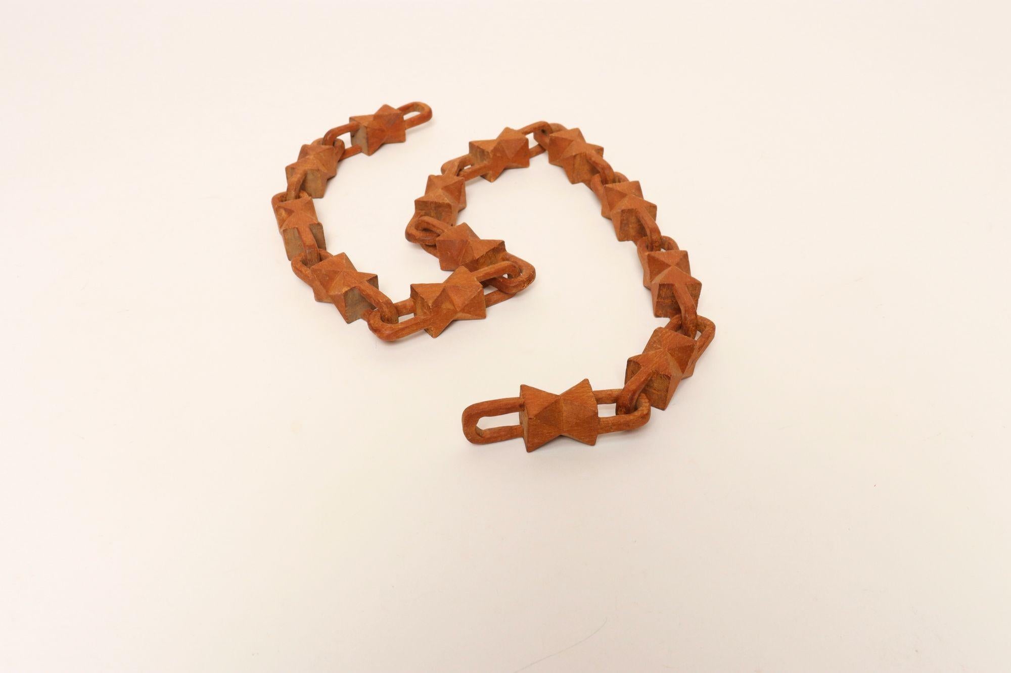 Chaîne fantaisiste d'art populaire taillée dans un seul morceau de bois (vers 1930/40, États-Unis).
Forme unique avec un motif de nœud papillon sculpté sur toute la surface.
Très bon état, vintage, avec patine / usure correspondant à l'âge et à