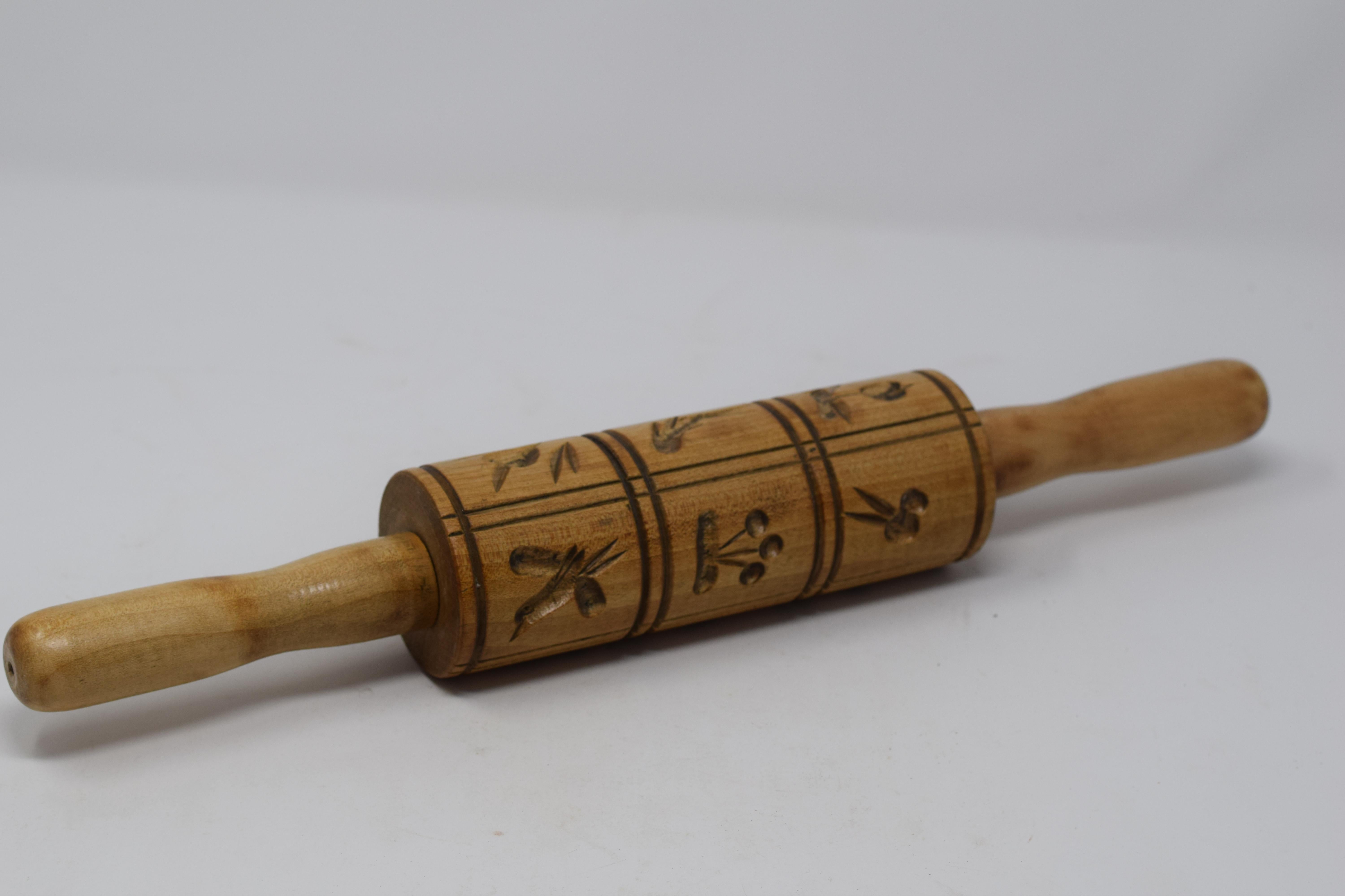 This vintage carved wood rolling pin is used to make Springerle, a type of German biscuit with an embossed design made by pressing a mold onto rolled dough and allowing the impression to dry before baking. The decorative pin features a collection of