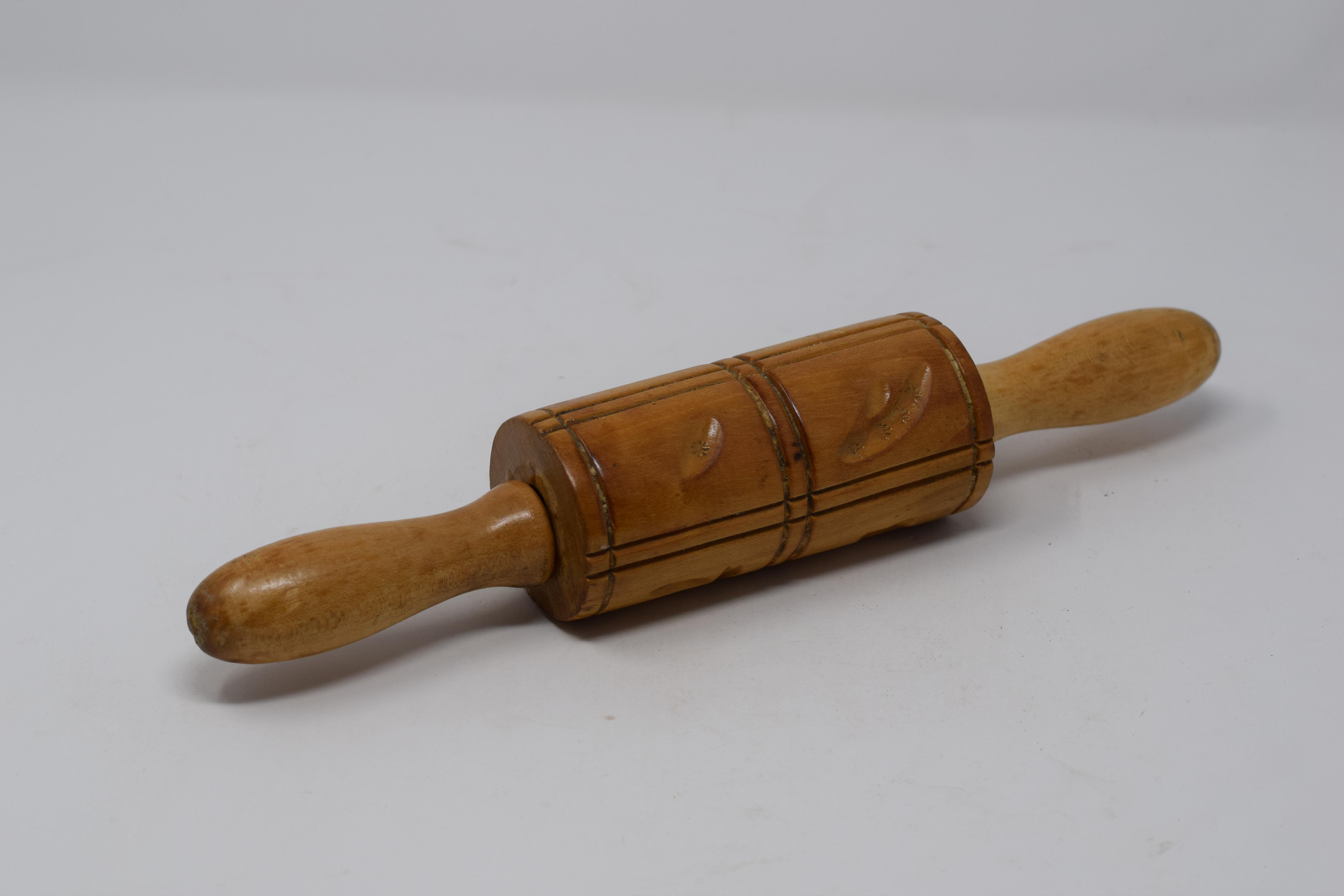 This vintage carved wood rolling pin is used to make Springerle, a type of German biscuit with an embossed design made by pressing a mold onto rolled dough and allowing the impression to dry before baking. The decorative pin features a collection of