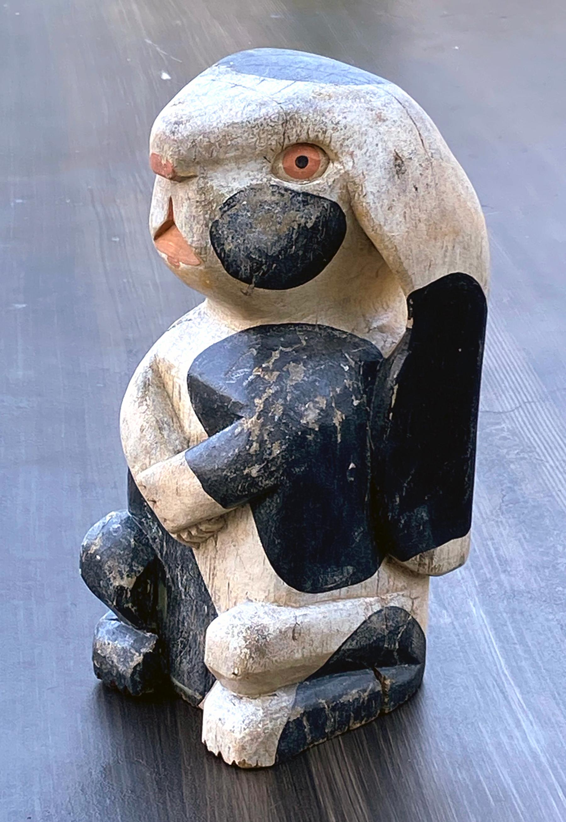 Lapin en bois de style Folk Art, vers les années 1940, canadien. Longues oreilles et bras croisés avec une tête de style Picasso. Le lapin est assis bien droit sur ses hanches en bois sculpté polychromé.