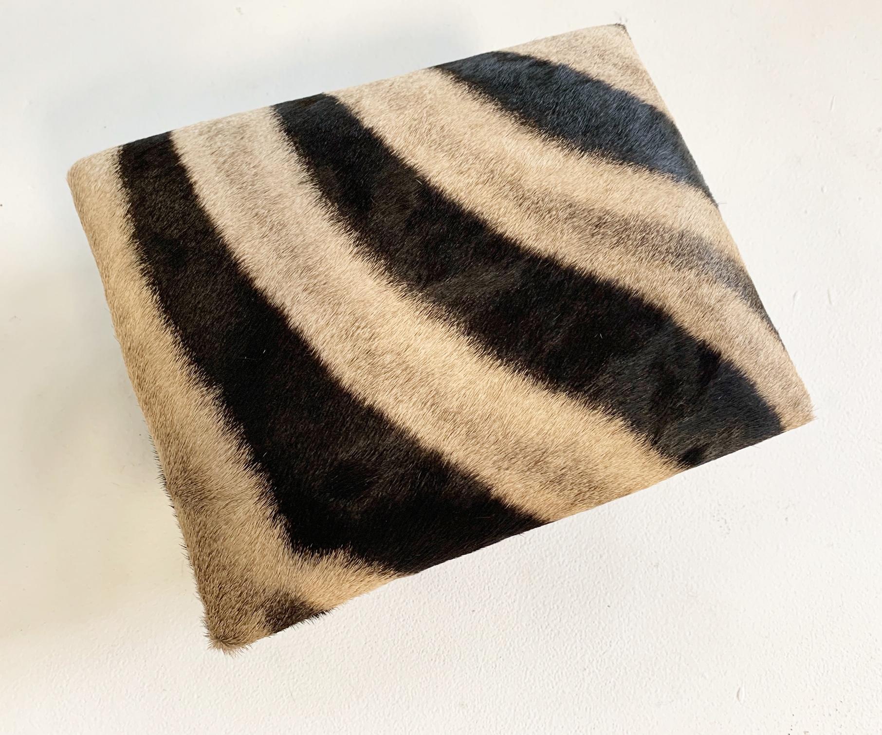 Upholstered in beautiful zebra hide, this handy foot stool is the perfect accent piece. We love the carved legs.