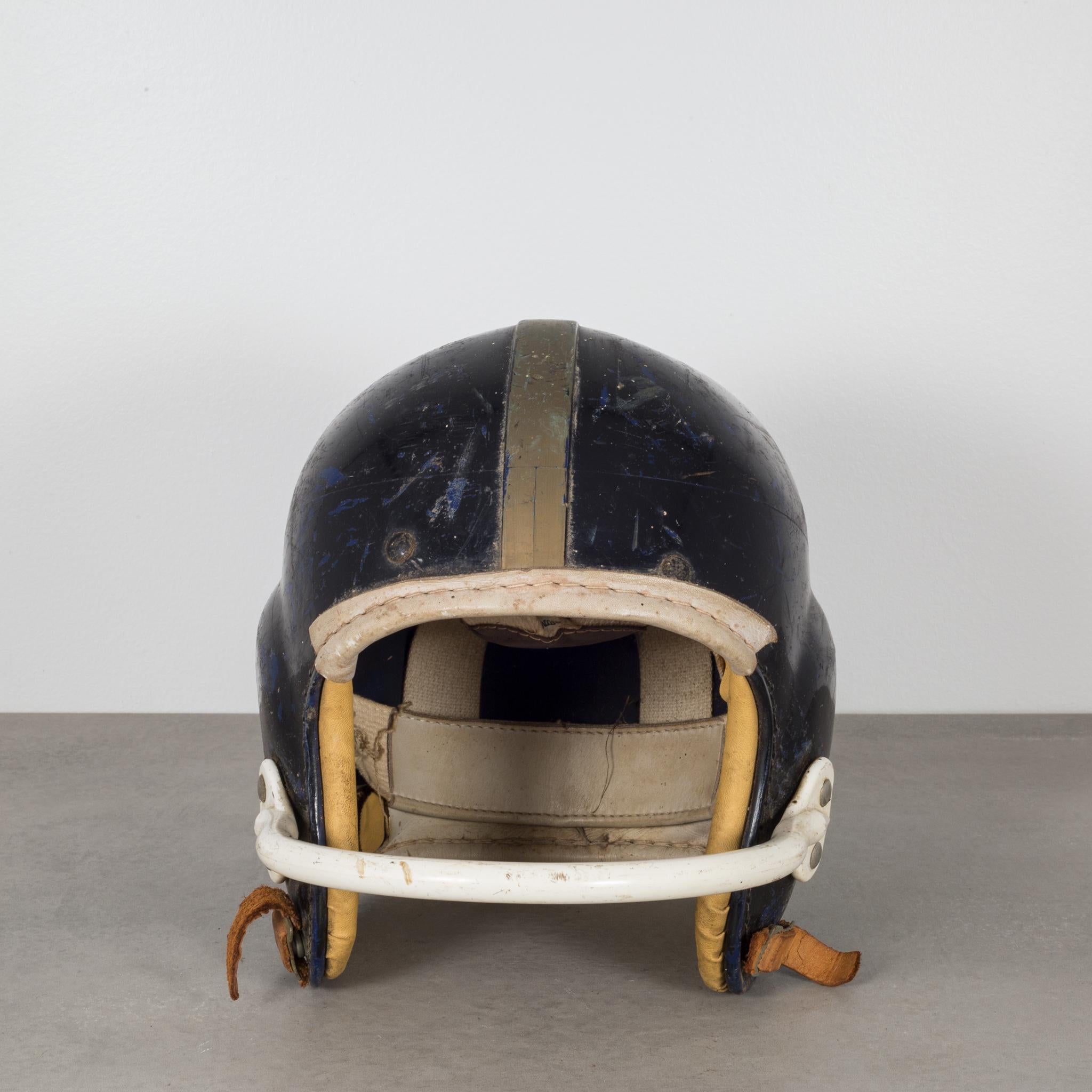 About
An original vintage football helmet with a single bar face mask. The helmet is black with a gold stripe running down the center, white face bar, and leather cushion on the forehead and back of the head. A 